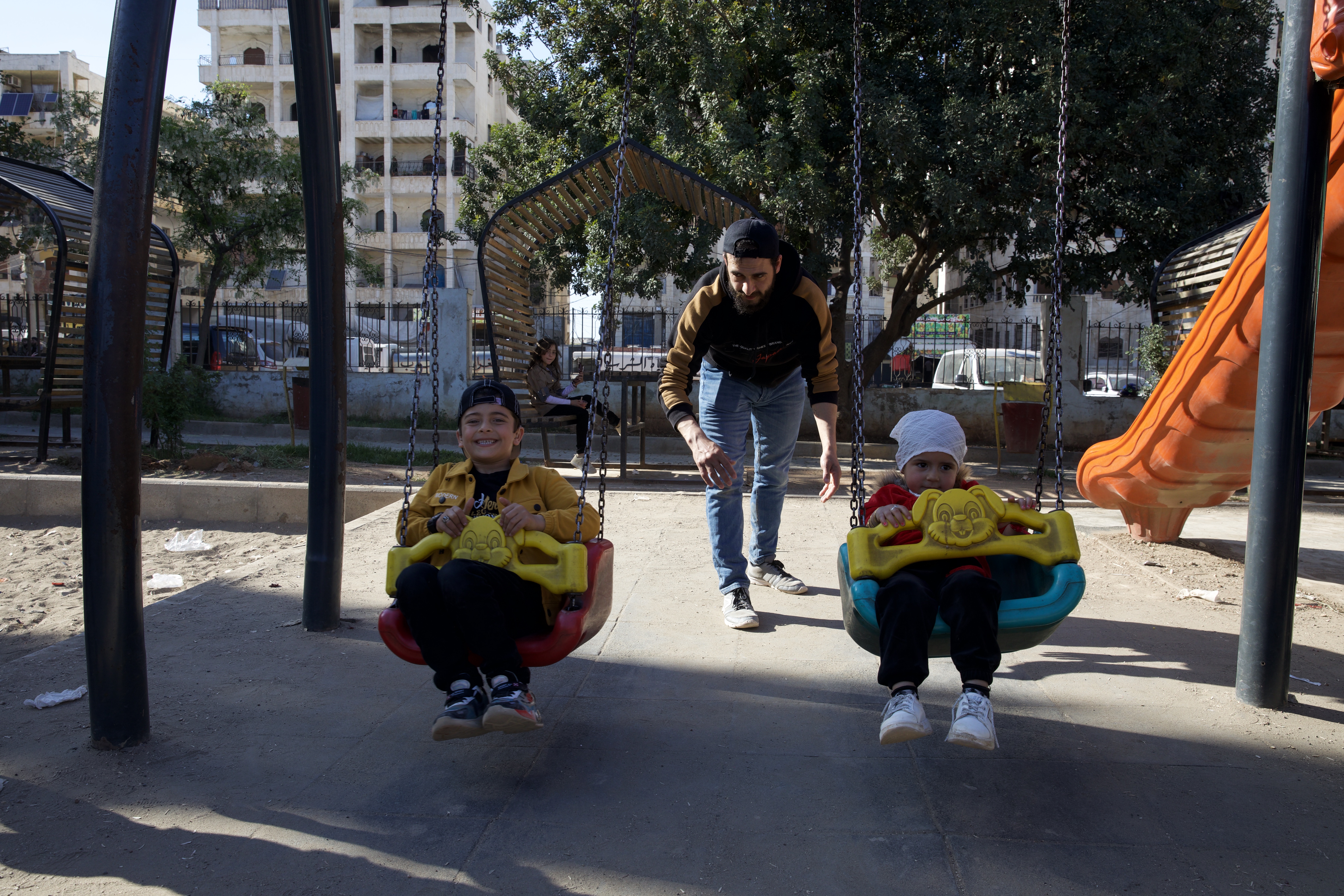 Khalid pushes the excited kids on the swings