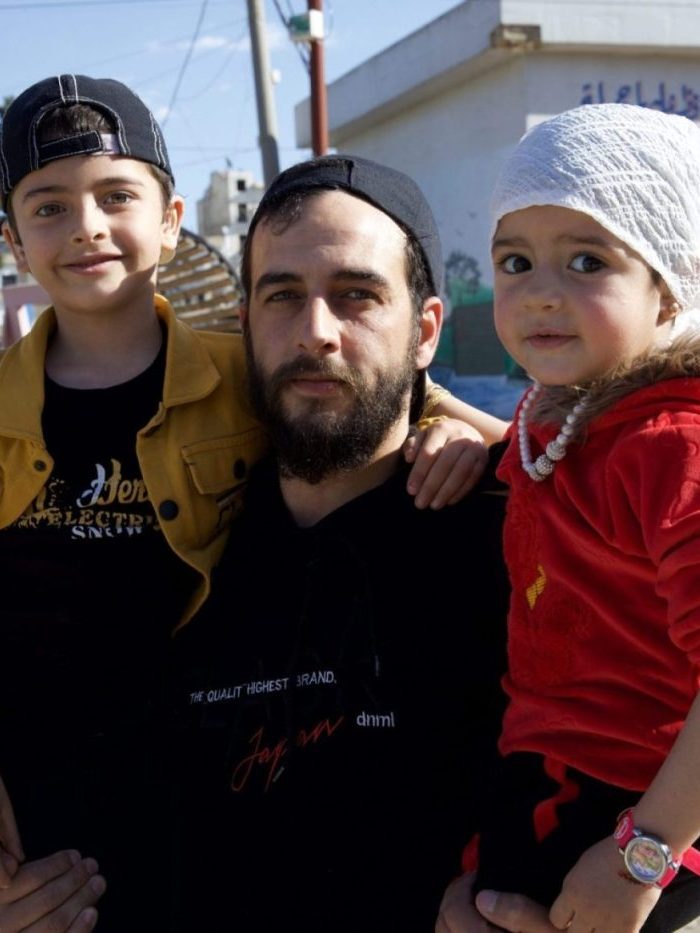Khalid holding the two kids for a photo home in Idlib, Syria