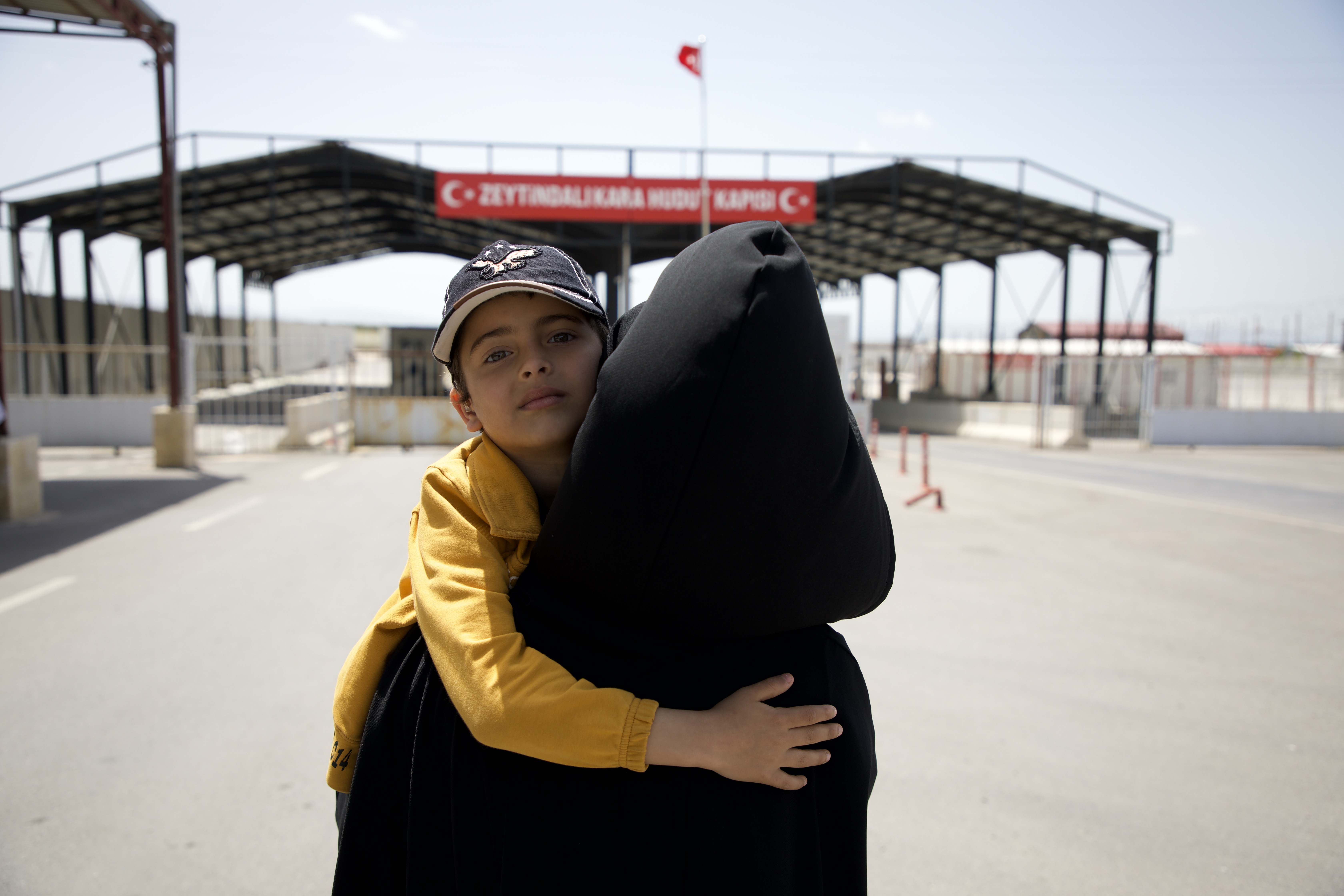 Fatima's back is turned, Aslan looks at us over her shoulder at the border crossing from Syria to Turkey