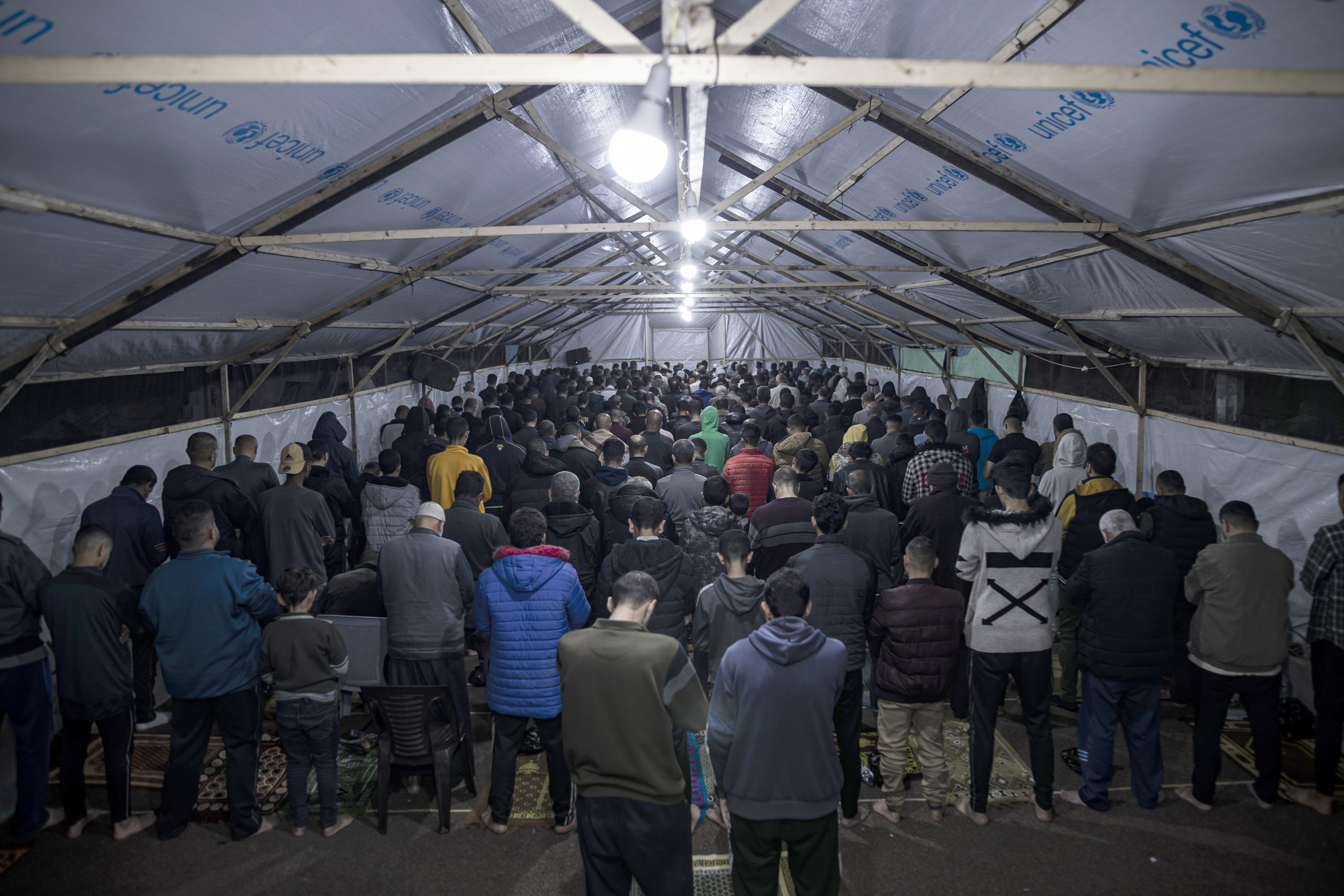 Palestinians gather to perform prayer on the night of Laylat al-Qadr in and outside the tent they have built near the debris of Faruq Mosque in Rafah, Gaza