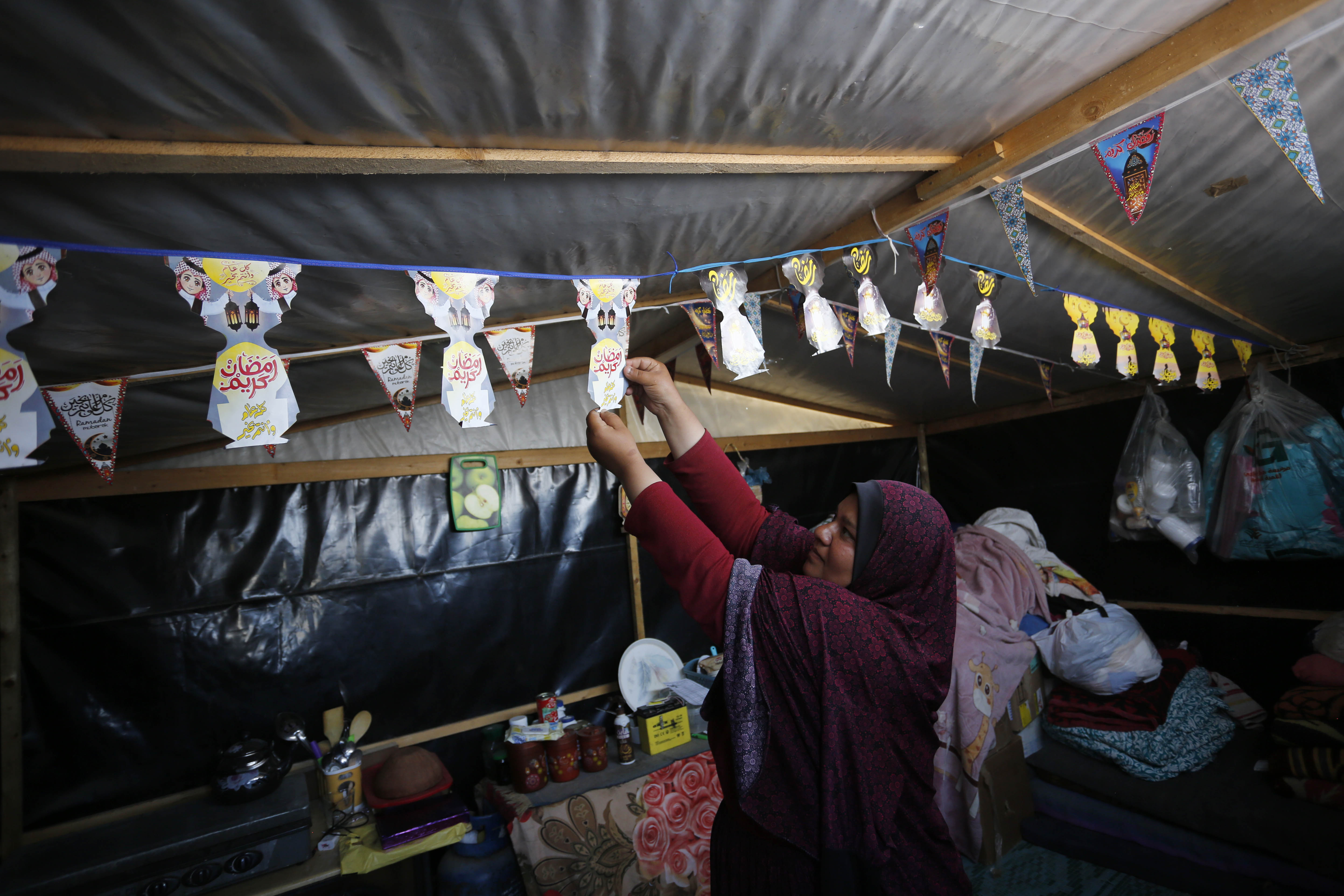 Palestinians hang decorations they prepared specially for Ramadan in their tents.