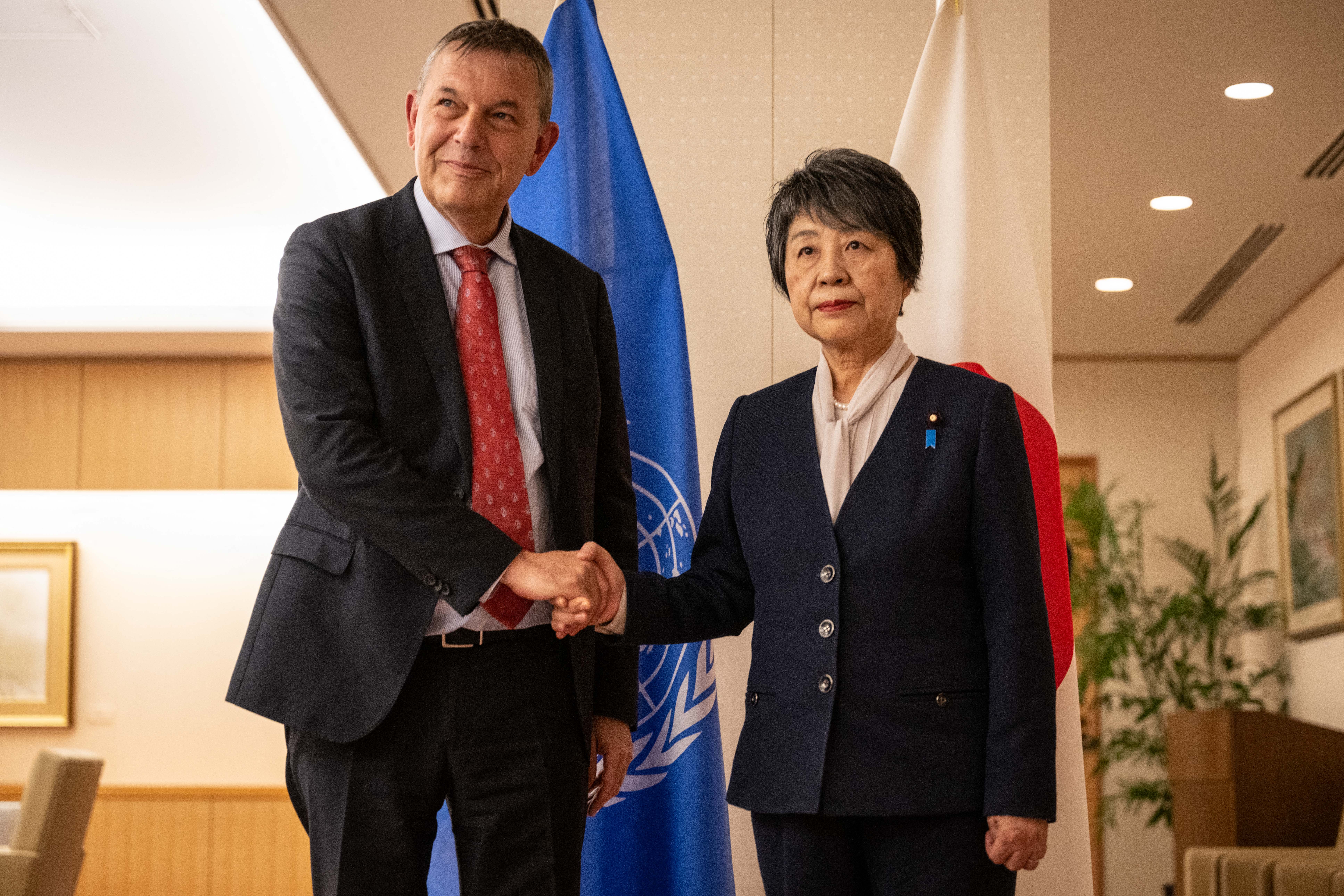 a man and a woman shake hands in front of a blue flag