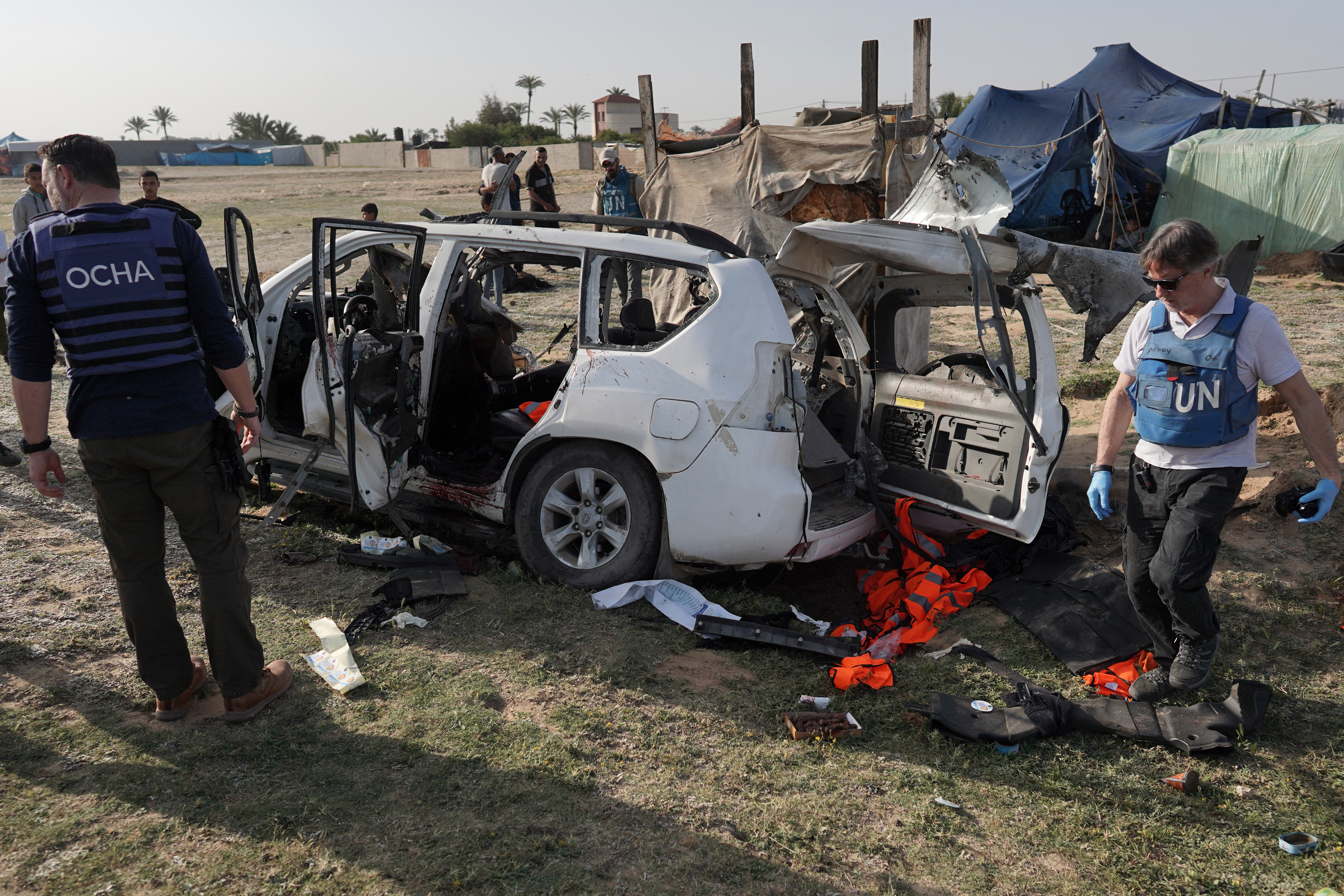 UN staff inspect the remains of a car used by US-based aid group World Central Kitchen that was hit by an Israeli air raid in Deir el-Balah in the central Gaza Strip on April 2, 2024
