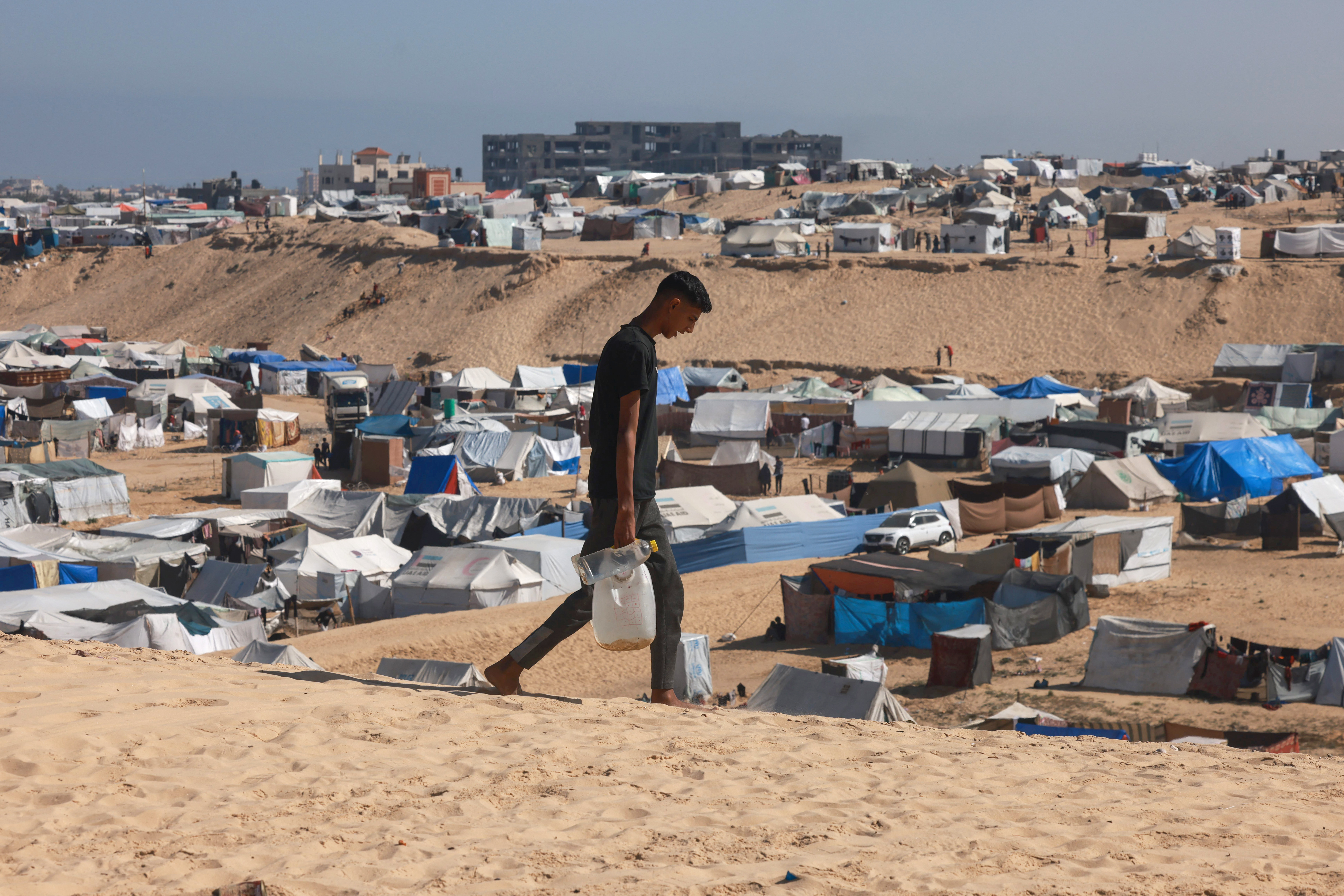 A Palestinian man ferries water at a makeshift camp for displaced people in Rafah in the southern Gaza Strip on April 4