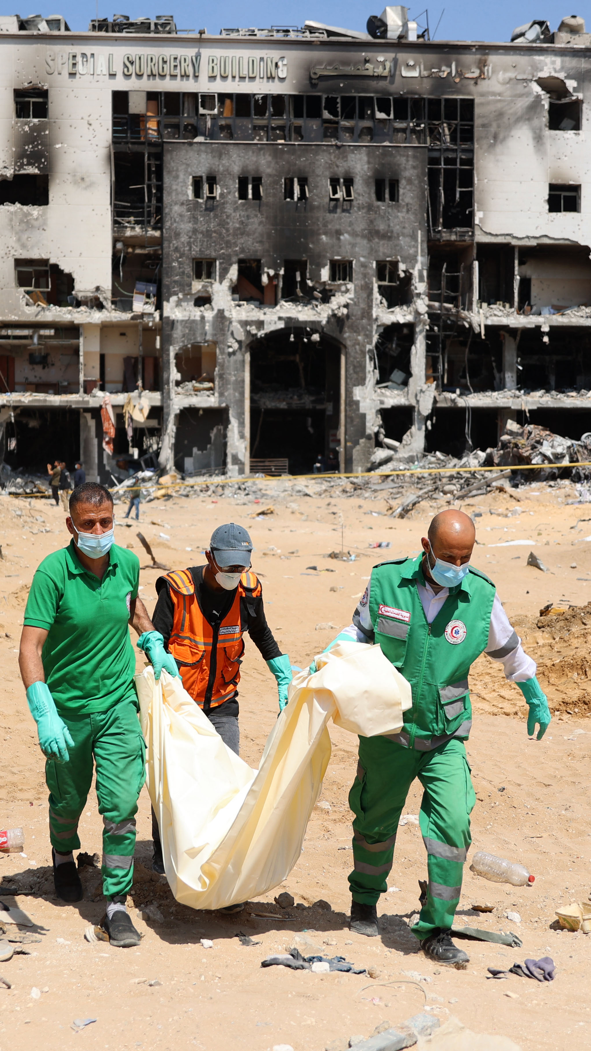 Palestinian forensic and civil defence workers recover human remains on the grounds of al-Shifa Hospital, April 8 [AFP]