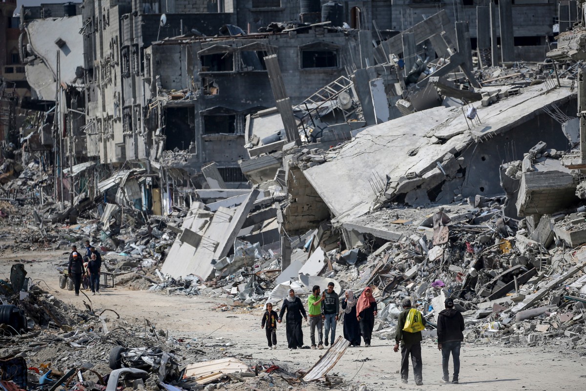 People walk amid the rubble of buildings destroyed during Israeli bombardment in Khan Yunis, on the southern Gaza Strip on April 16, 2024 [AFP]