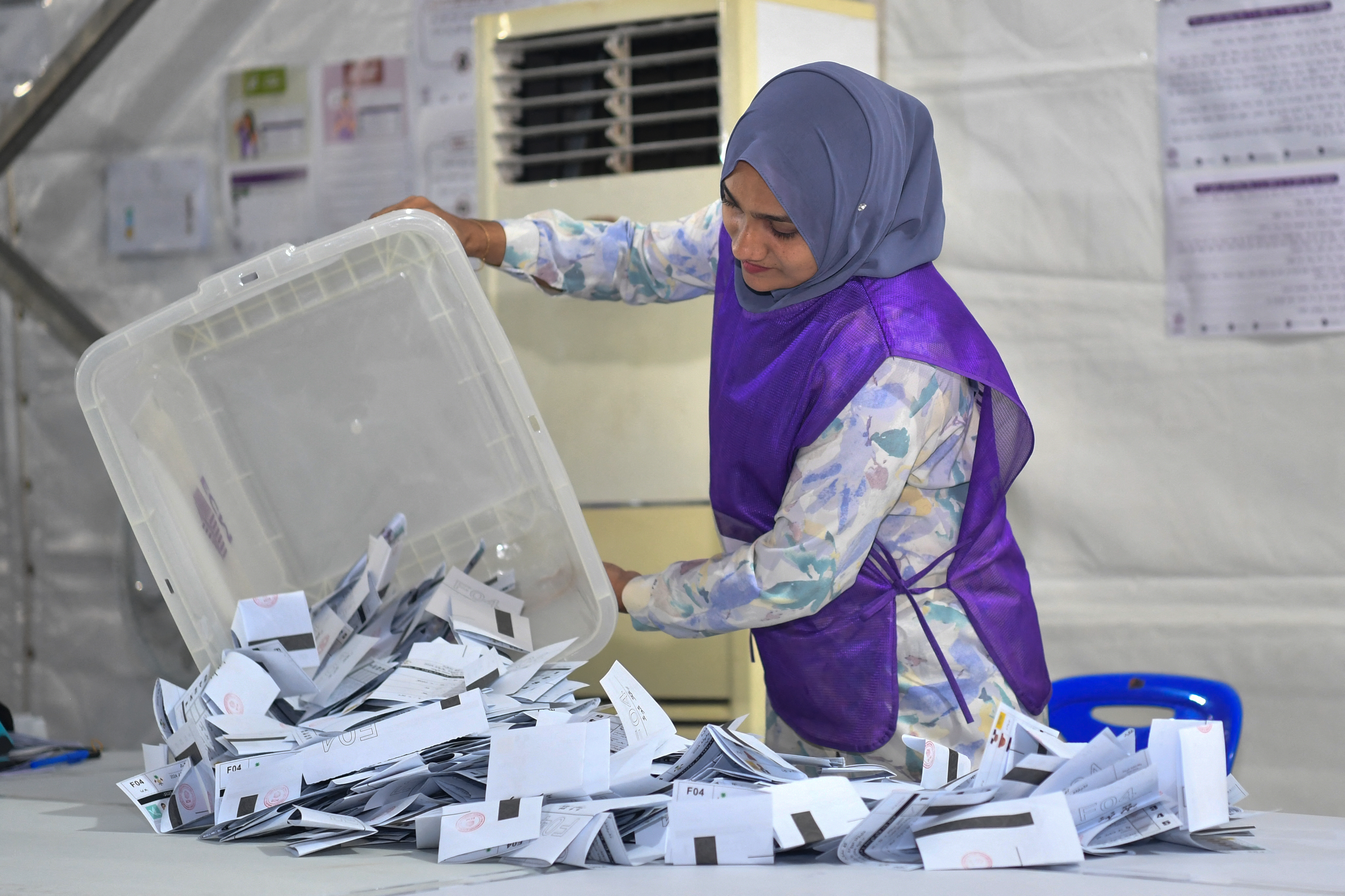 An election official empties a box of votes onto a table to start the count.