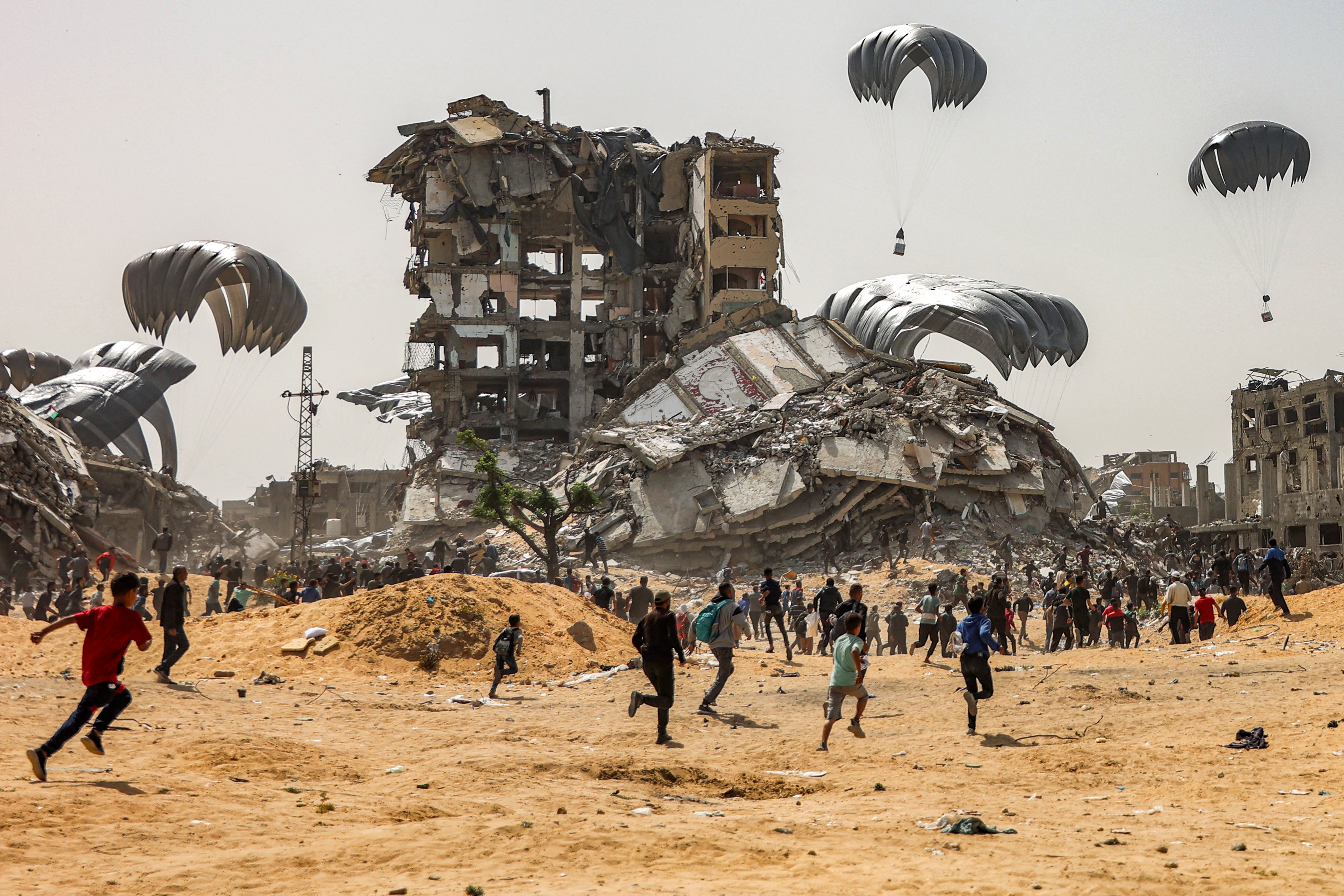 People rush to landing humanitarian aid packages dropped over the northern Gaza Strip
