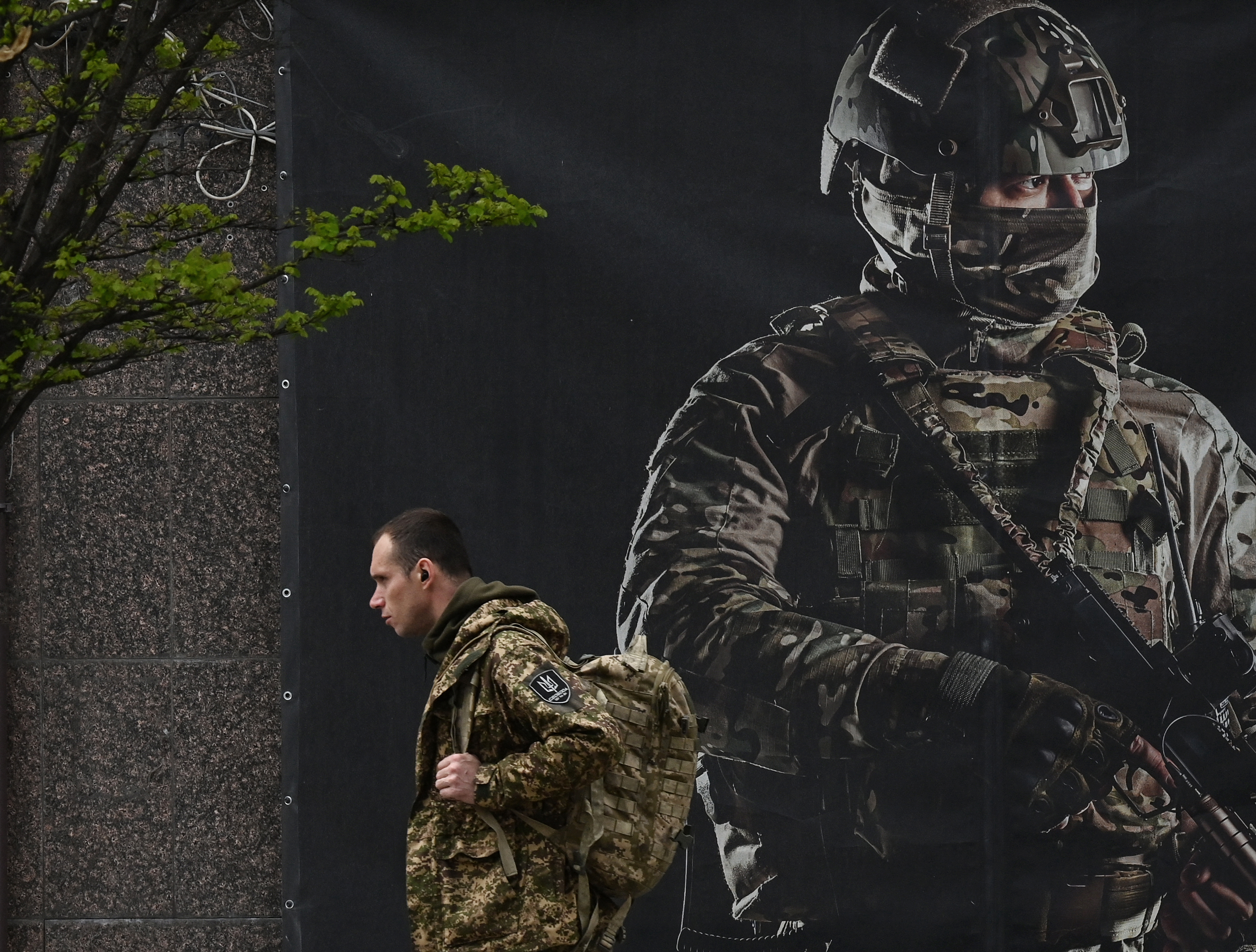 A Ukrainian solider walking past a recruitment poster in Kyiv