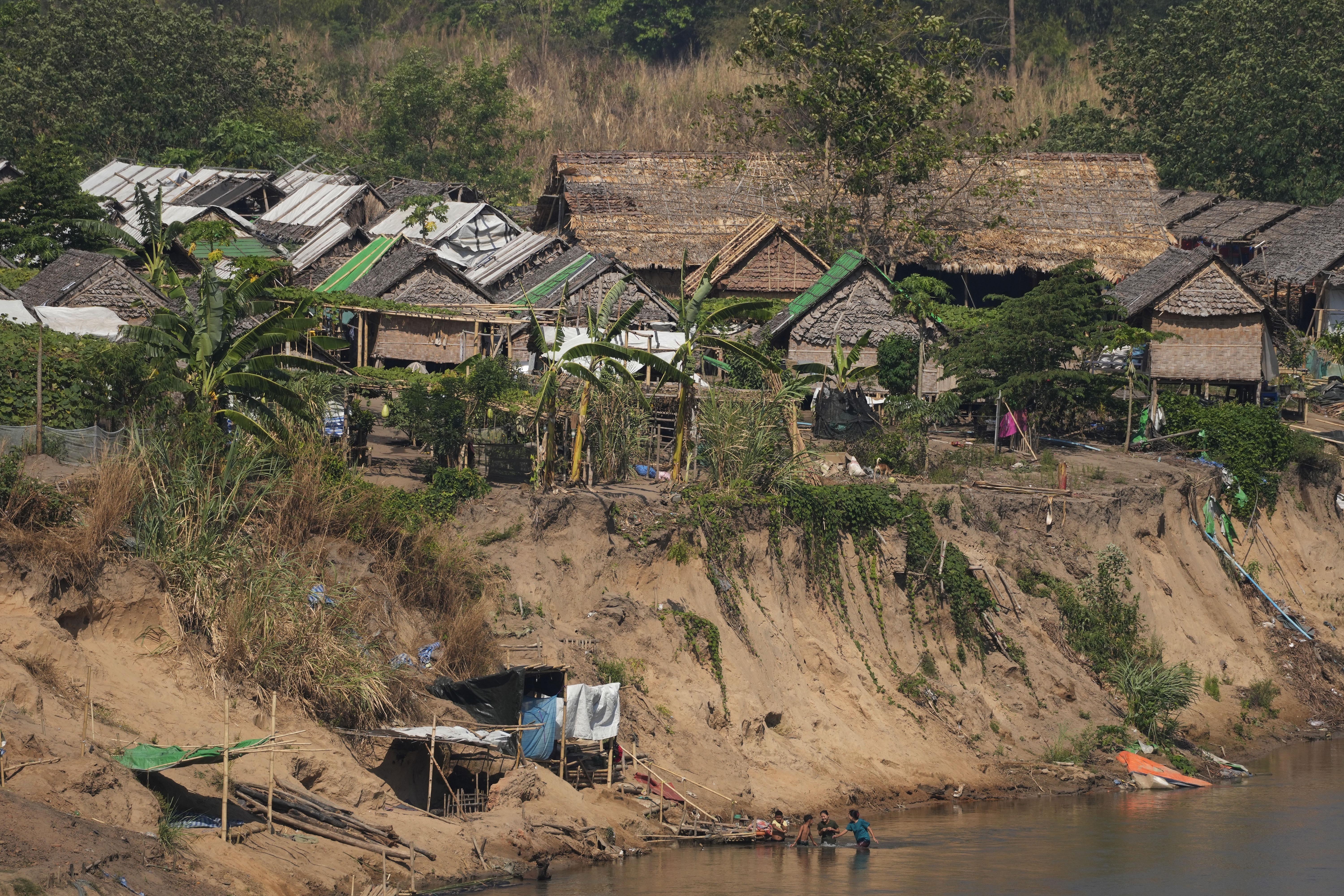A view of a camp for people displaced by the fighting in Myanmar. It's on the banks of the Moei river, which separates Myanmar from Thailand. The buildings are of bamboo and palm.
