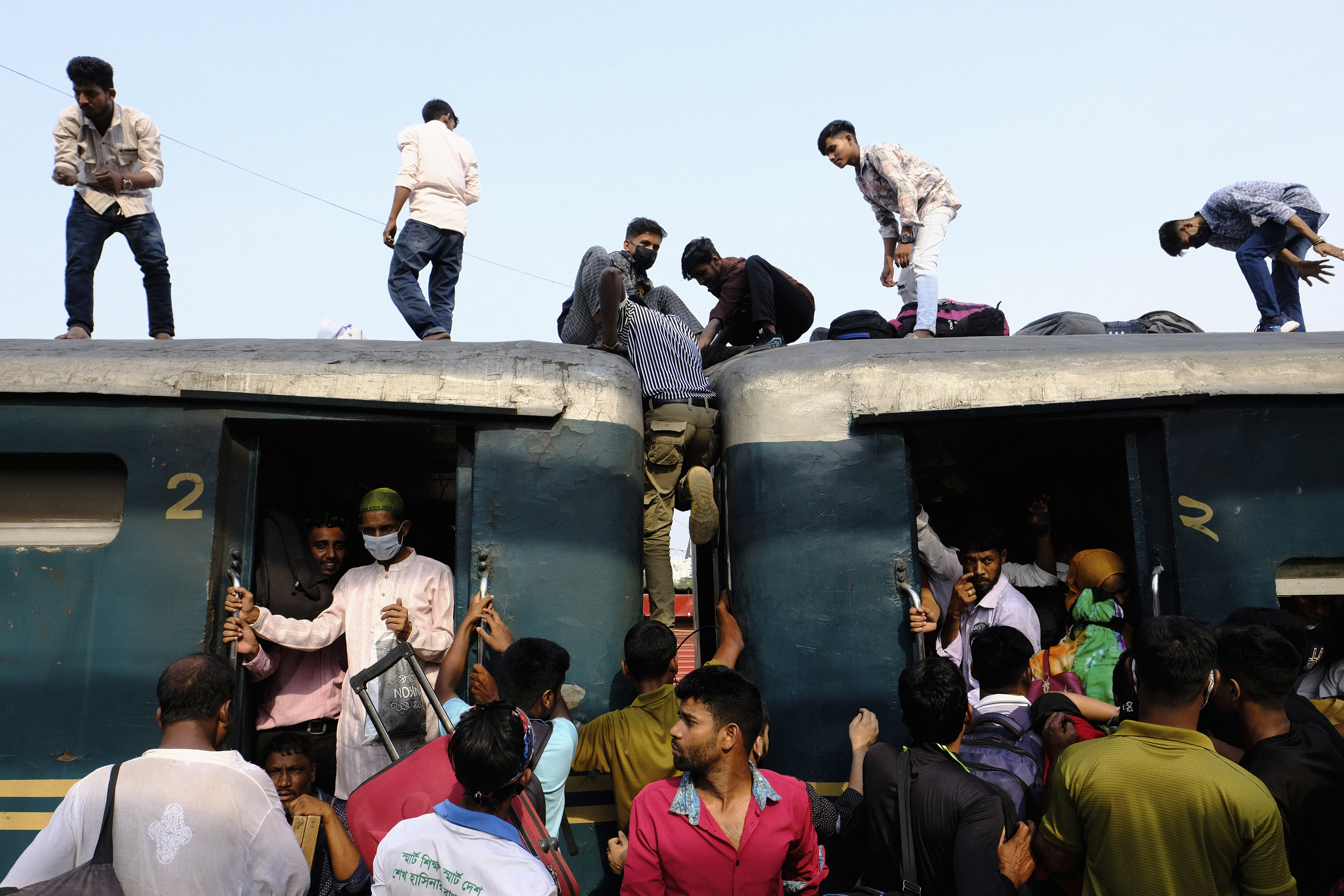 Bangladeshi Muslims maneuver their way on the roof of an overcrowded train to travel home for Eid al-Fitr celebrations, at a railway station in Dhaka, Bangladesh, Tuesday, April 9