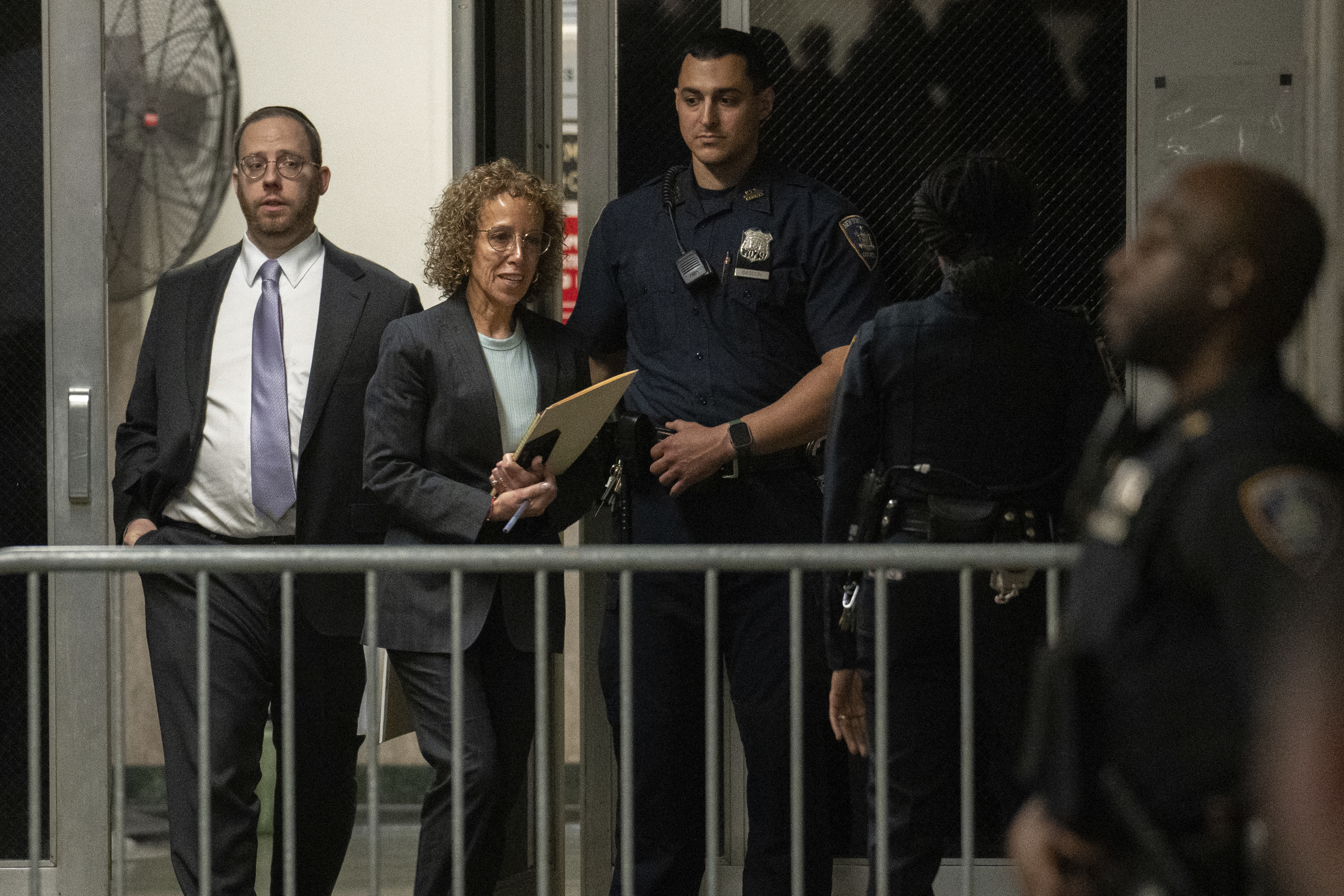 Susan Necheles walks out of the courthouse, which is barricaded by a temporary metal fence.