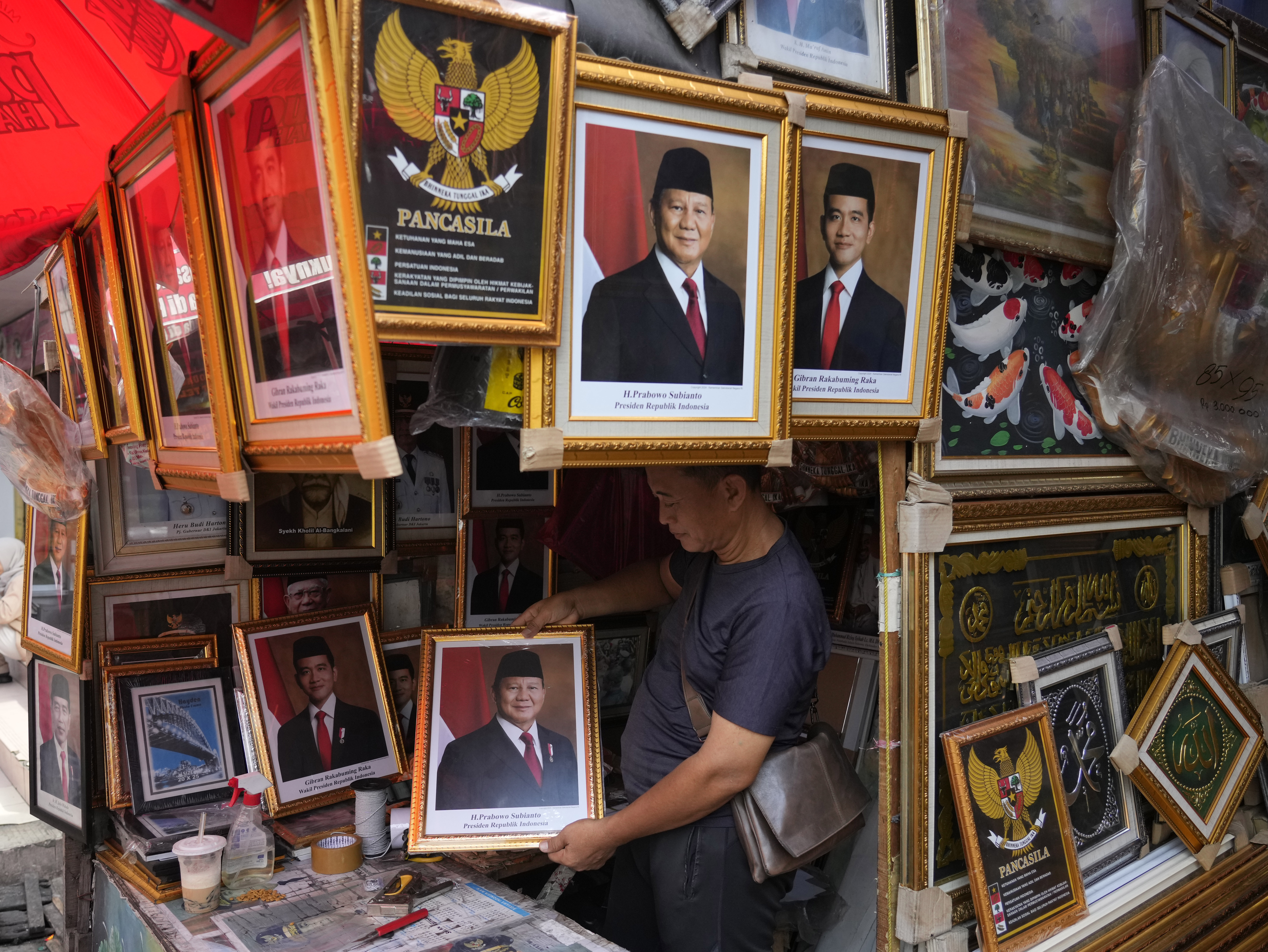 A vendor holds a portrait of Indonesian President-elect and Defense Minister Prabowo Subianto at a market in Jakarta, Indonesia, Wednesday, April 24