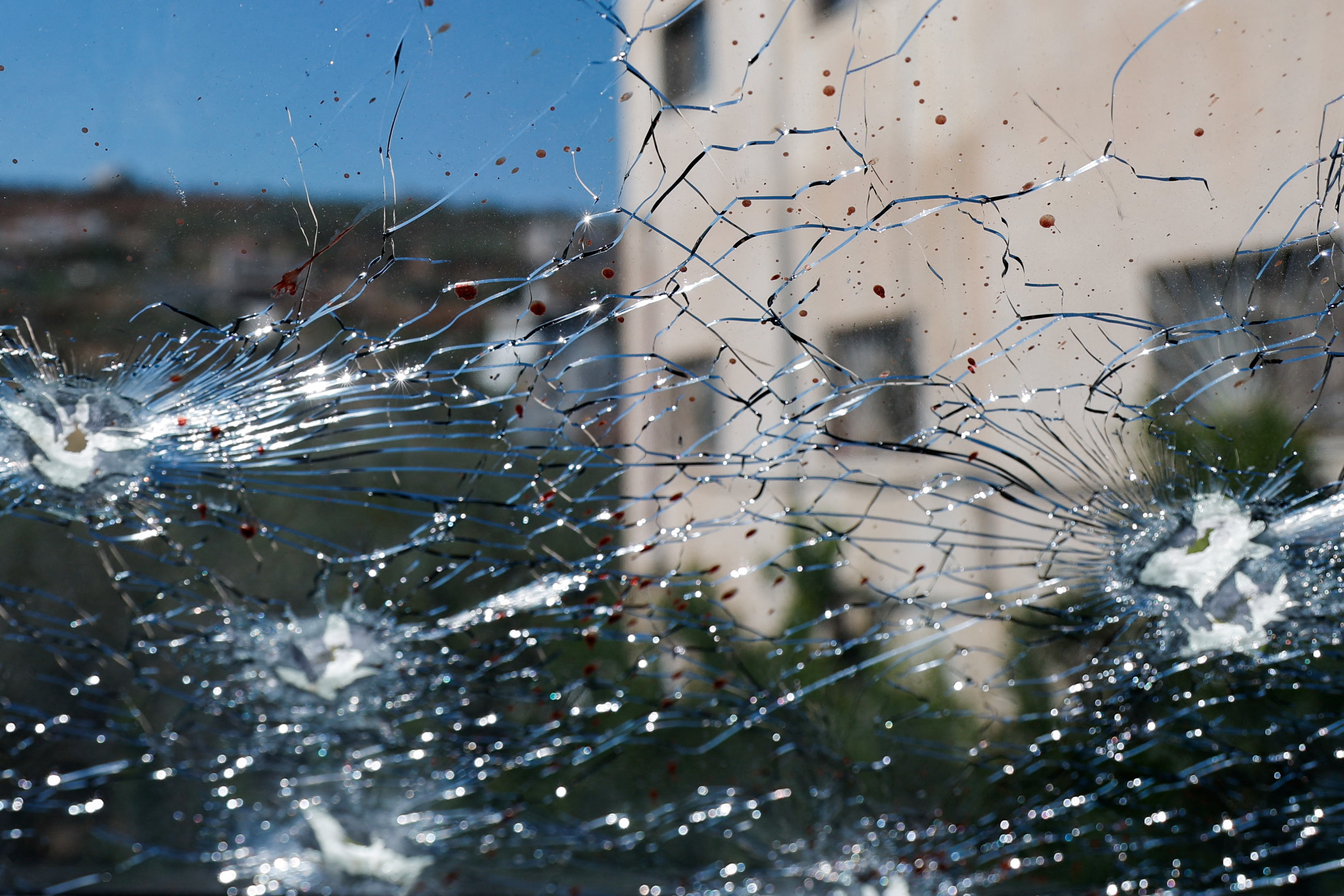 Blood and bullet holes are seen on the window of a damaged car