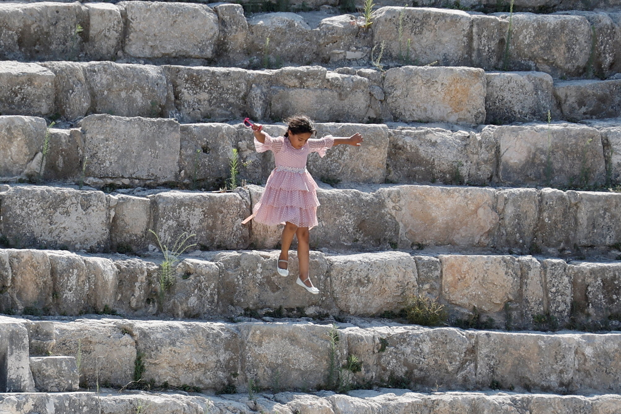 A Palestinian girl jumps on the stones of the Roman amphitheatre in Sebastia