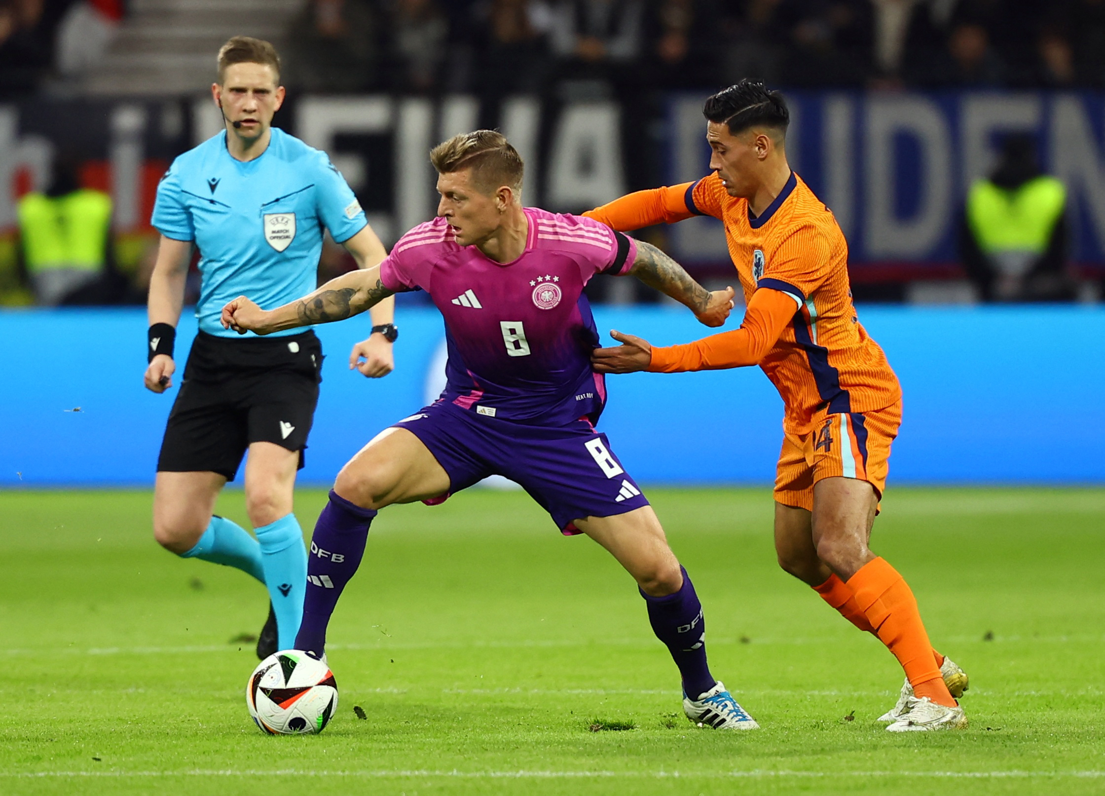 Football player protects ball against defender.