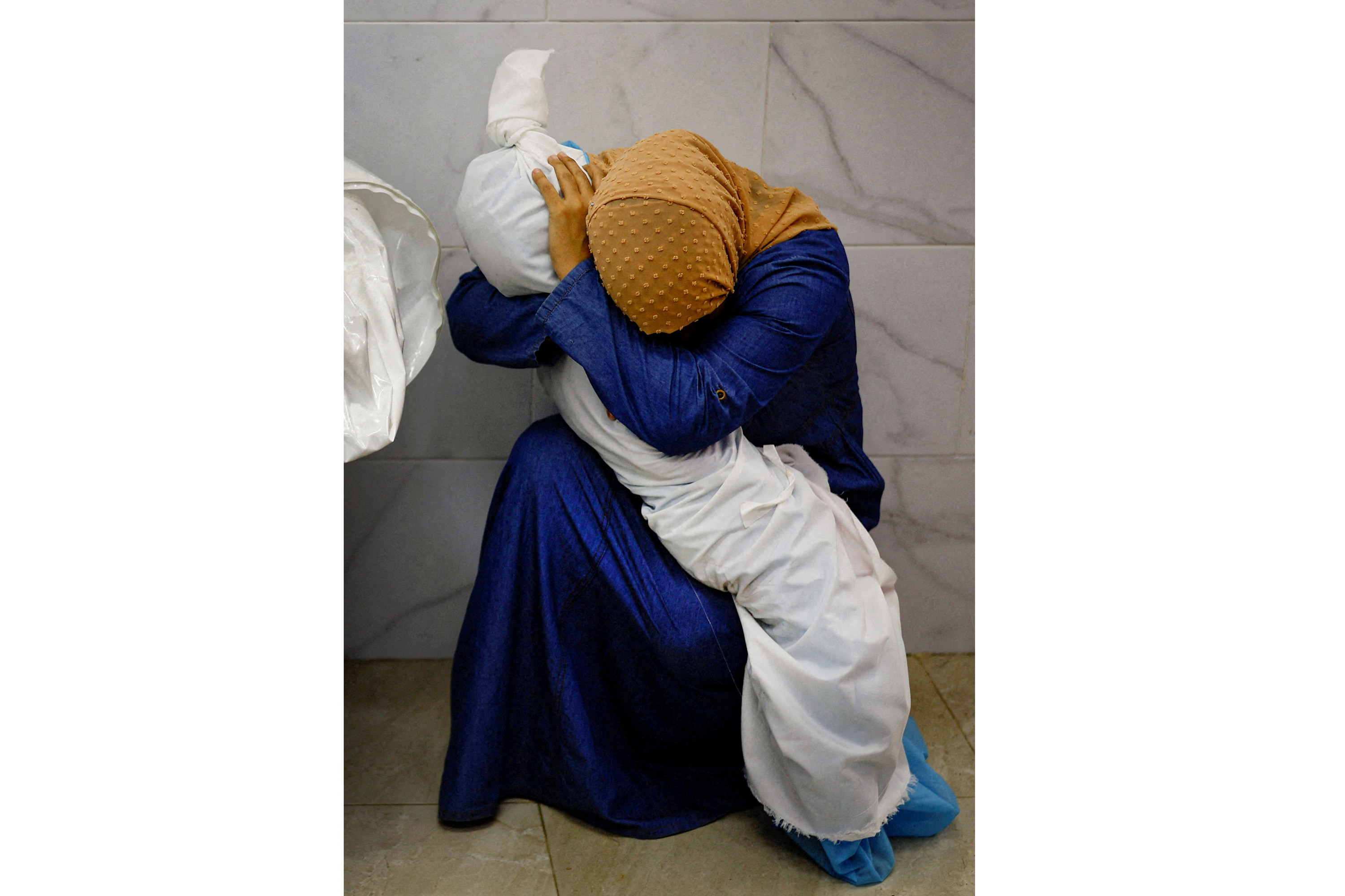 FILE PHOTO: Palestinian woman Inas Abu Maamar, 36, embraces the body of her 5-year-old niece Saly, who was killed in an Israeli strike, at Nasser hospital in Khan Younis in the southern Gaza Strip, October 17, 2023. Reuters photographer Mohammad Salem was in Khan Younis on Oct. 17 at the Nasser Hospital morgue, where residents were going to search for missing relatives. He saw Inas squatting on the ground in the morgue, sobbing and tightly embracing Saly's body. "I lost my conscience when I saw the girl, I took her in my arms," Inas said. "The doctor asked me to let go... but I told them to leave her with me." Mohammed Salem won the 2024 World Press Photo of the Year award for this image. REUTERS/Mohammed Salem/File Photo TPX IMAGES OF THE DAY