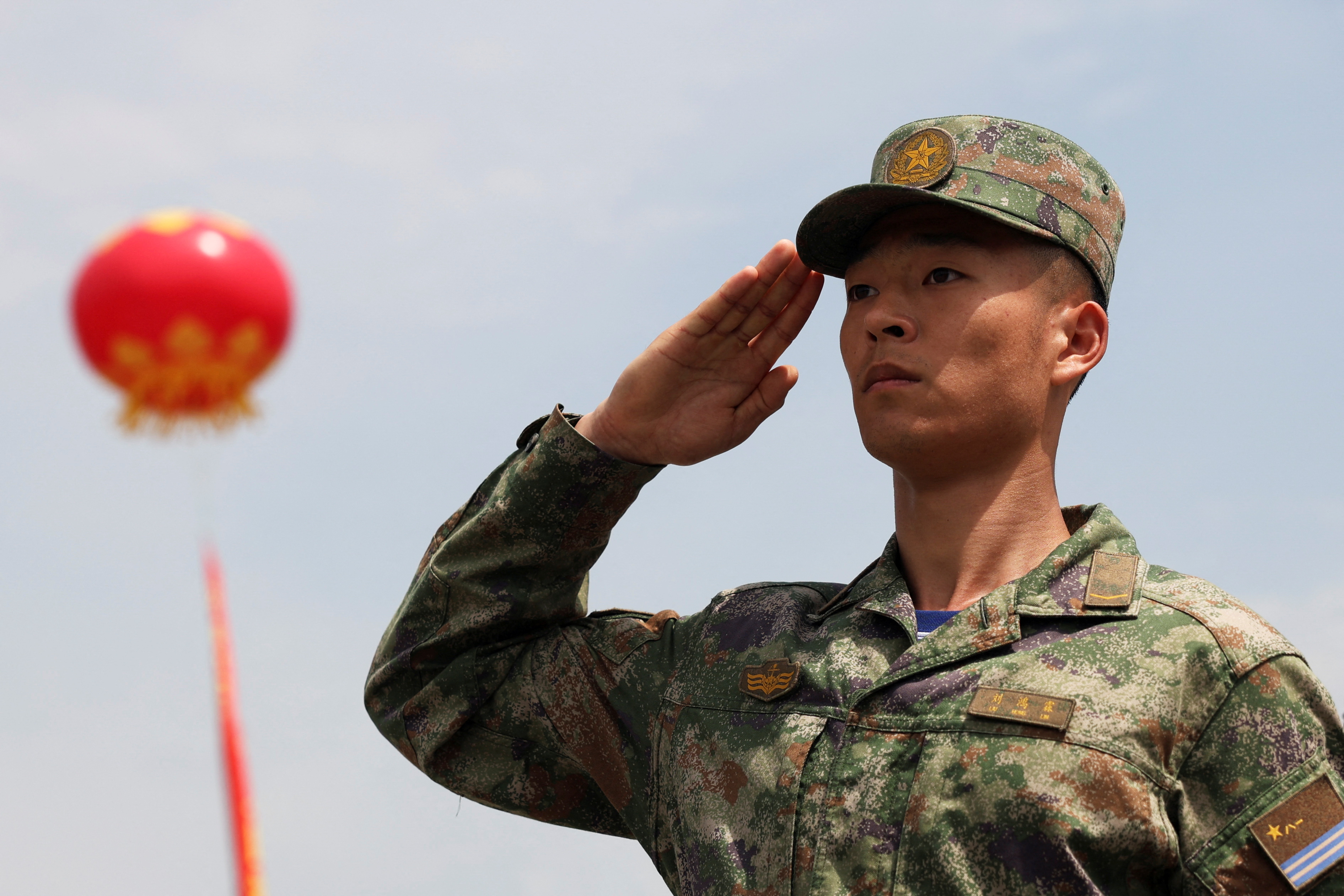 A member of the PLA navy saluting. A red lantern is hanging behind