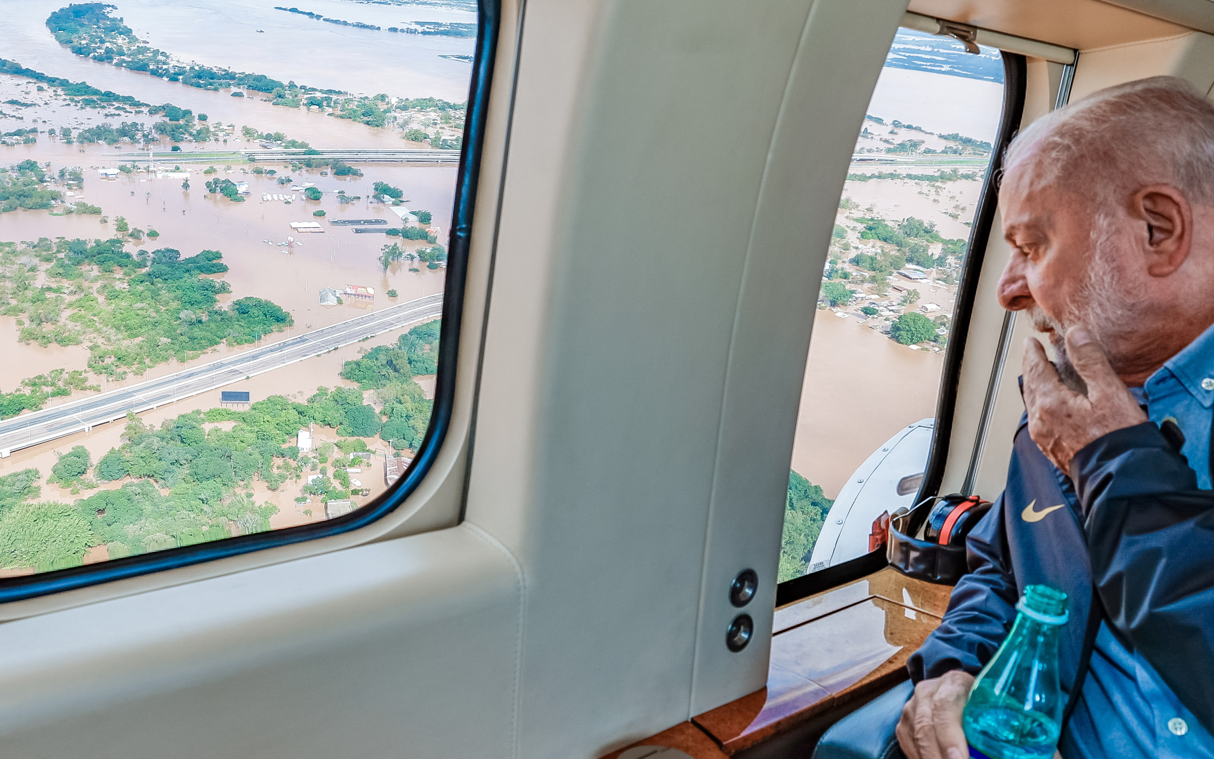President Luiz Inacio Lula da Silva looks out of a helicopter window onto floodwaters below.