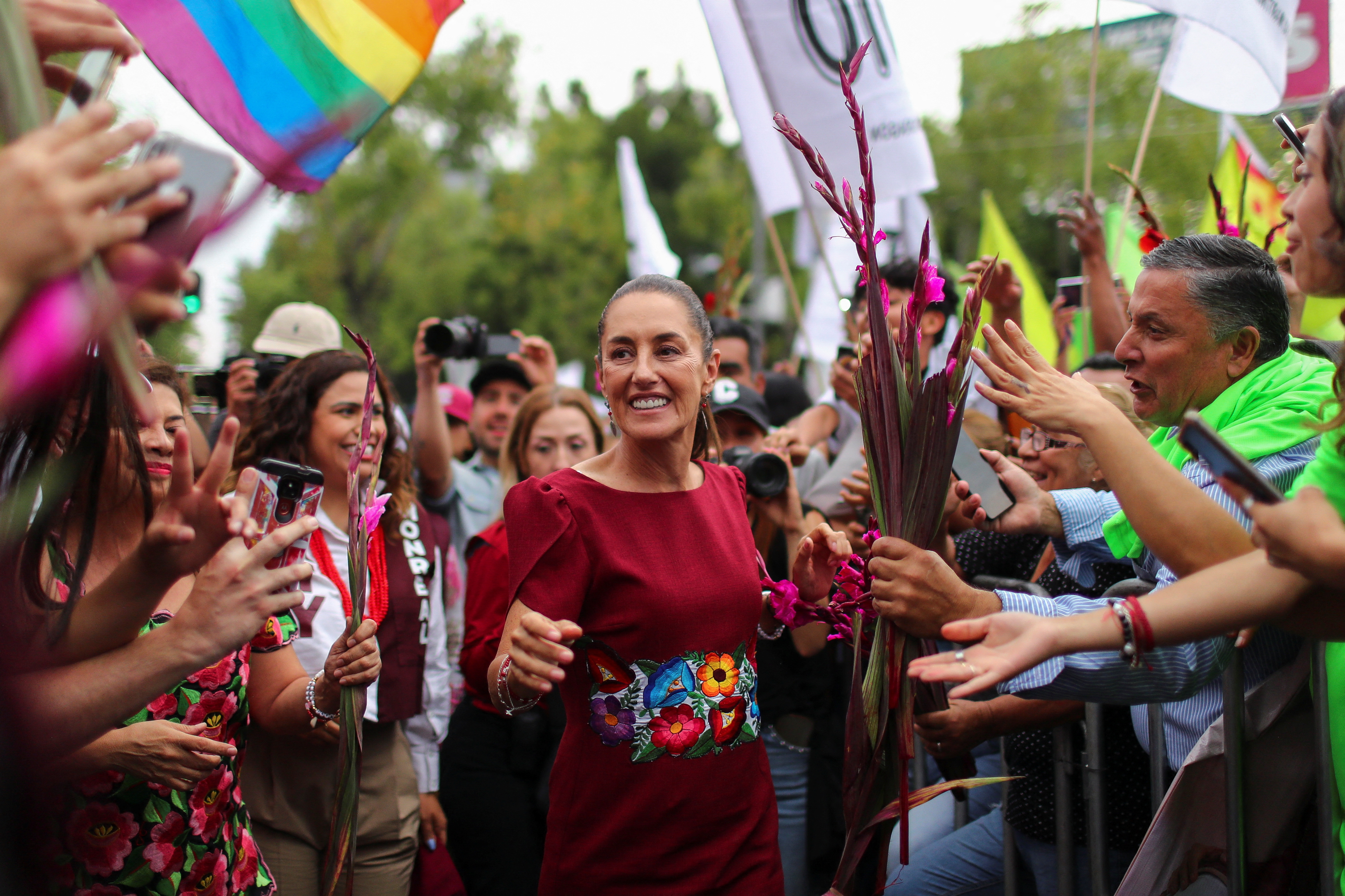 Claudia Sheinbaum greets a crowd of supporters at an outdoor rally.