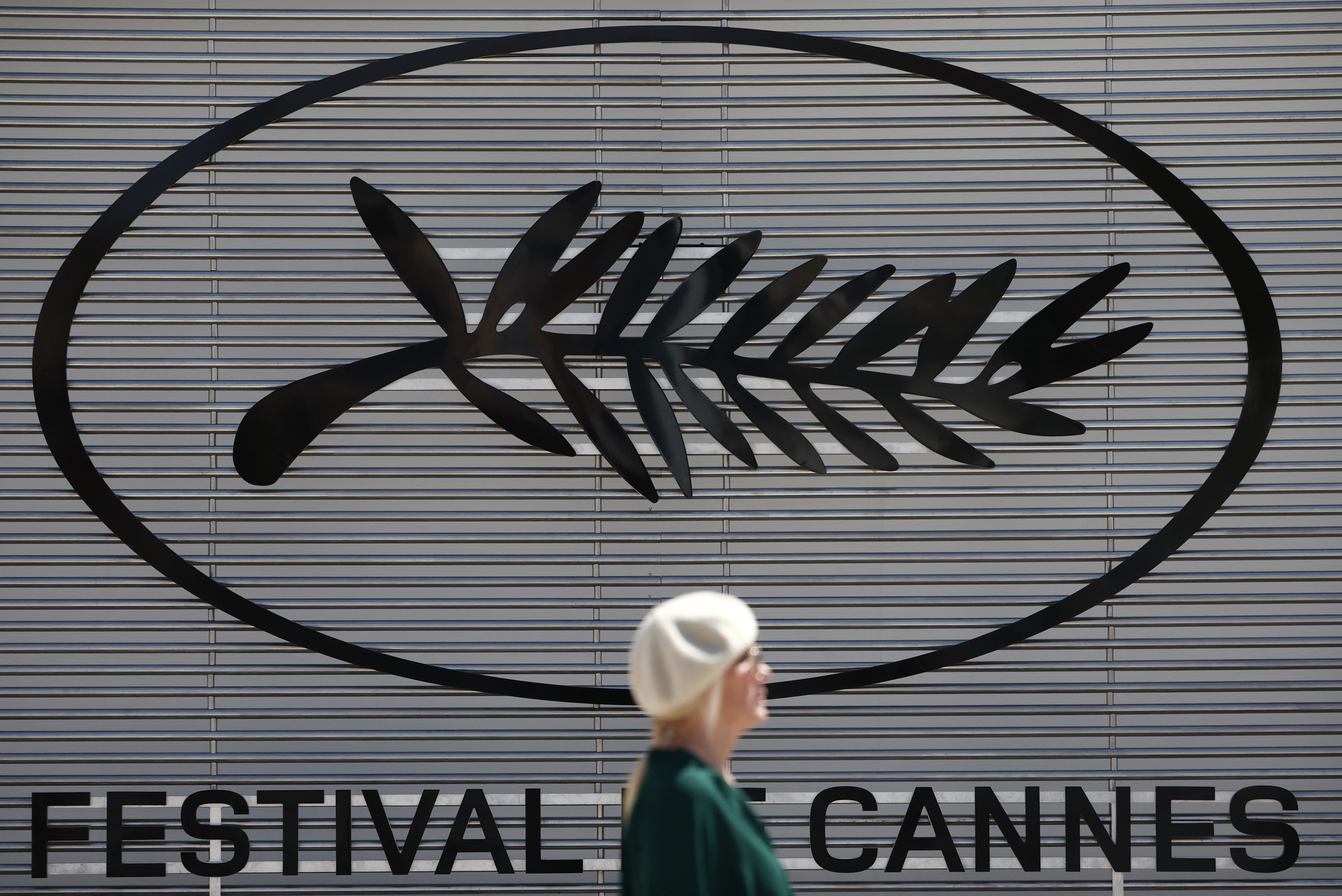 A woman walks past a Palme d'Or symbol on the eve of the opening of the 77th Cannes Film Festival in Cannes, France, May 13, 2024. REUTERS/Stephane Mahe