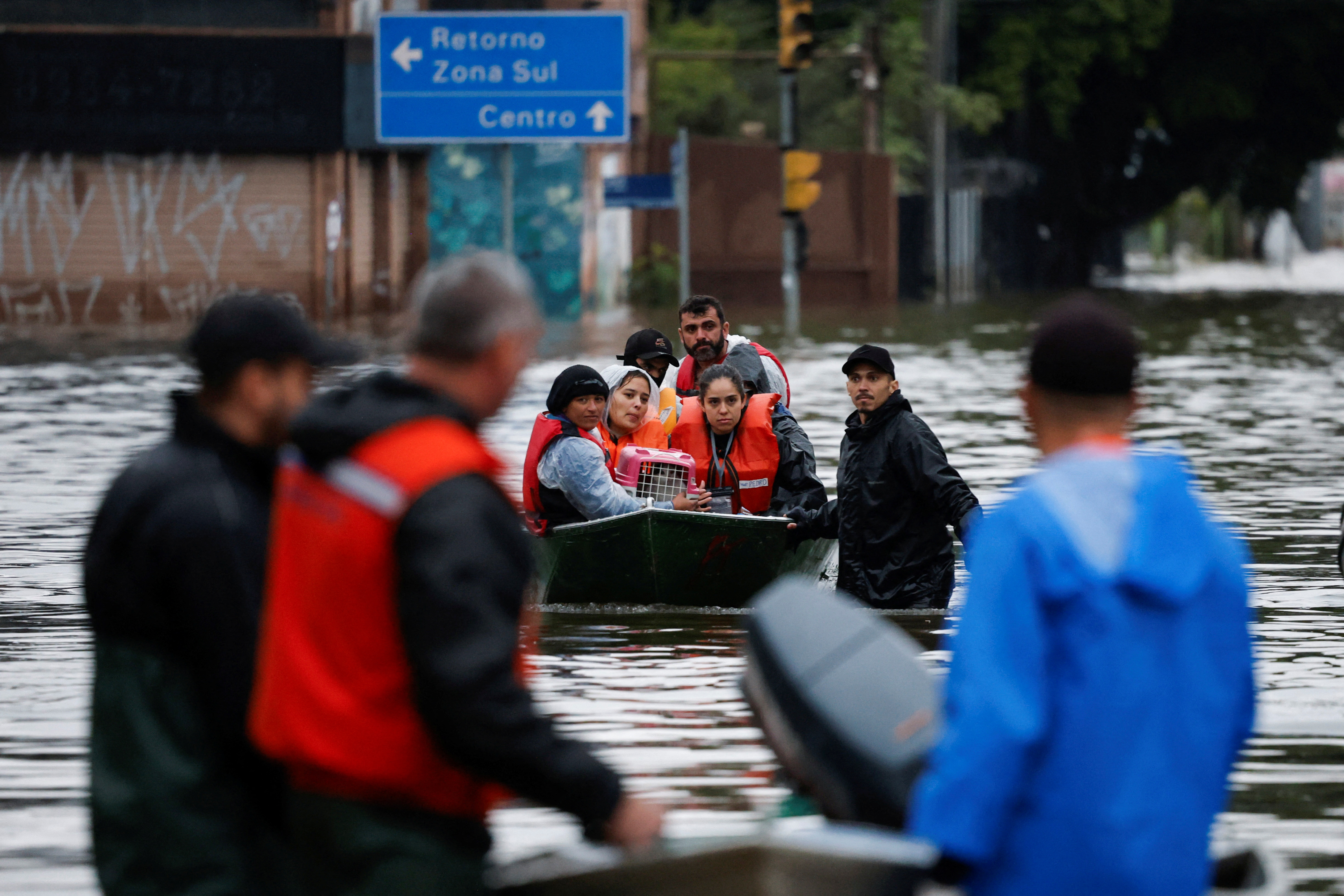Volunteers and evacuees ride in a small inflatable motor boat, as they approach more helpers addressing the floodwaters in Porto Alegre, Brazil.