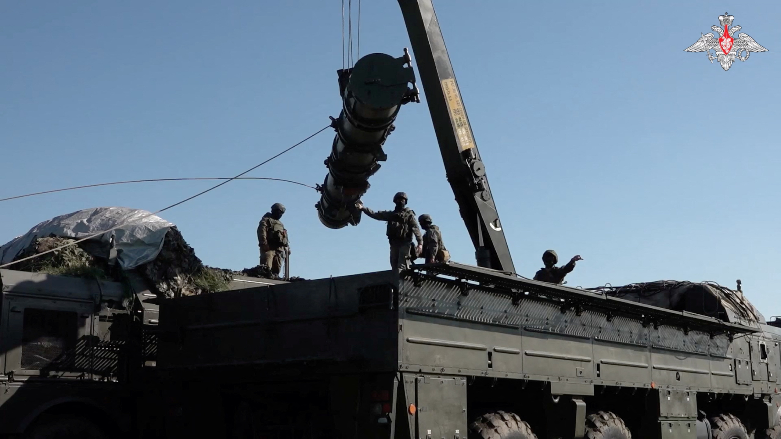 Russian soldiers on top of an an Iskander missile launching system capable of carrying a nuclear warhead. A weapon appears o be lifted by a crane system into the air