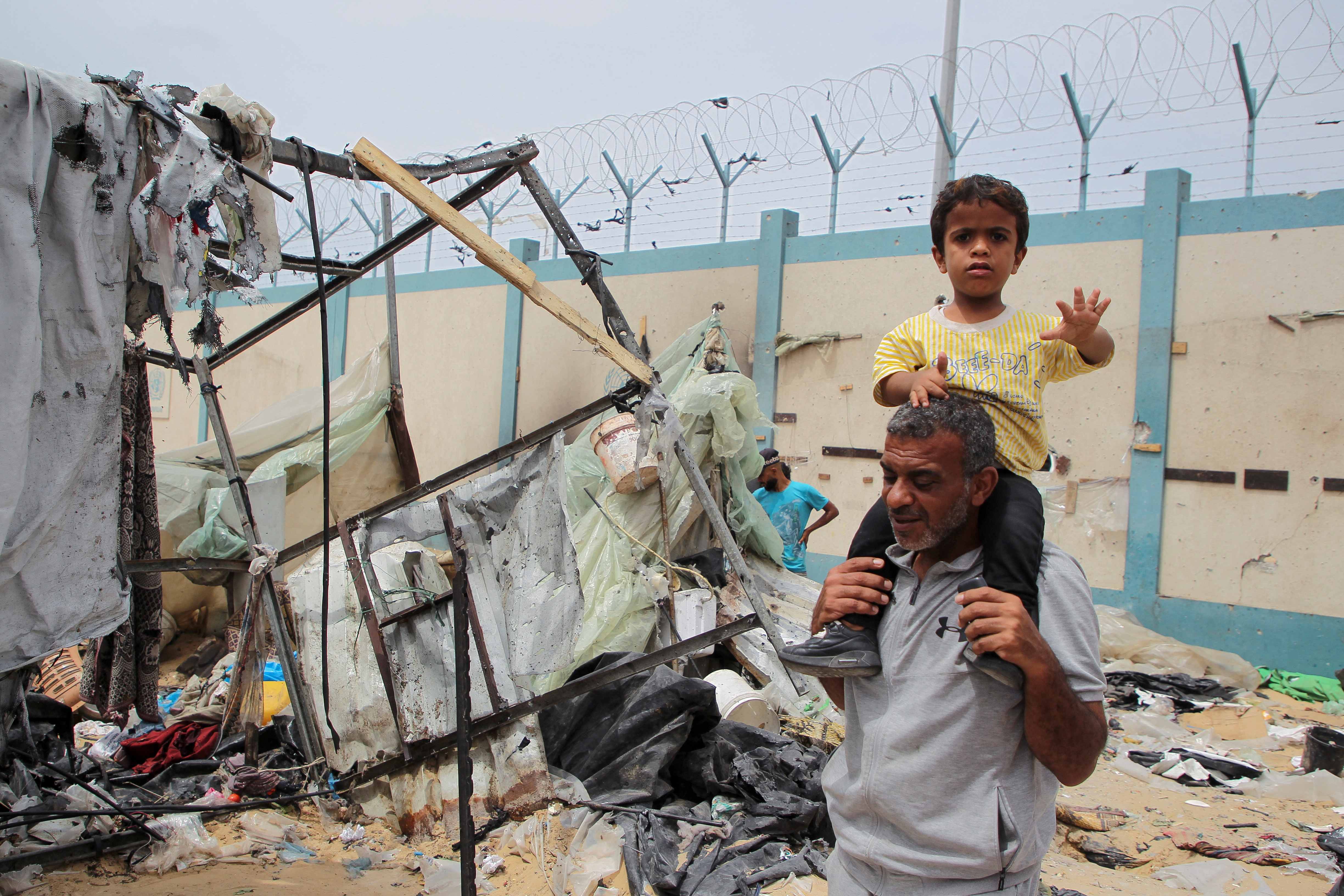 Man holds child on his shoulders amid destruction