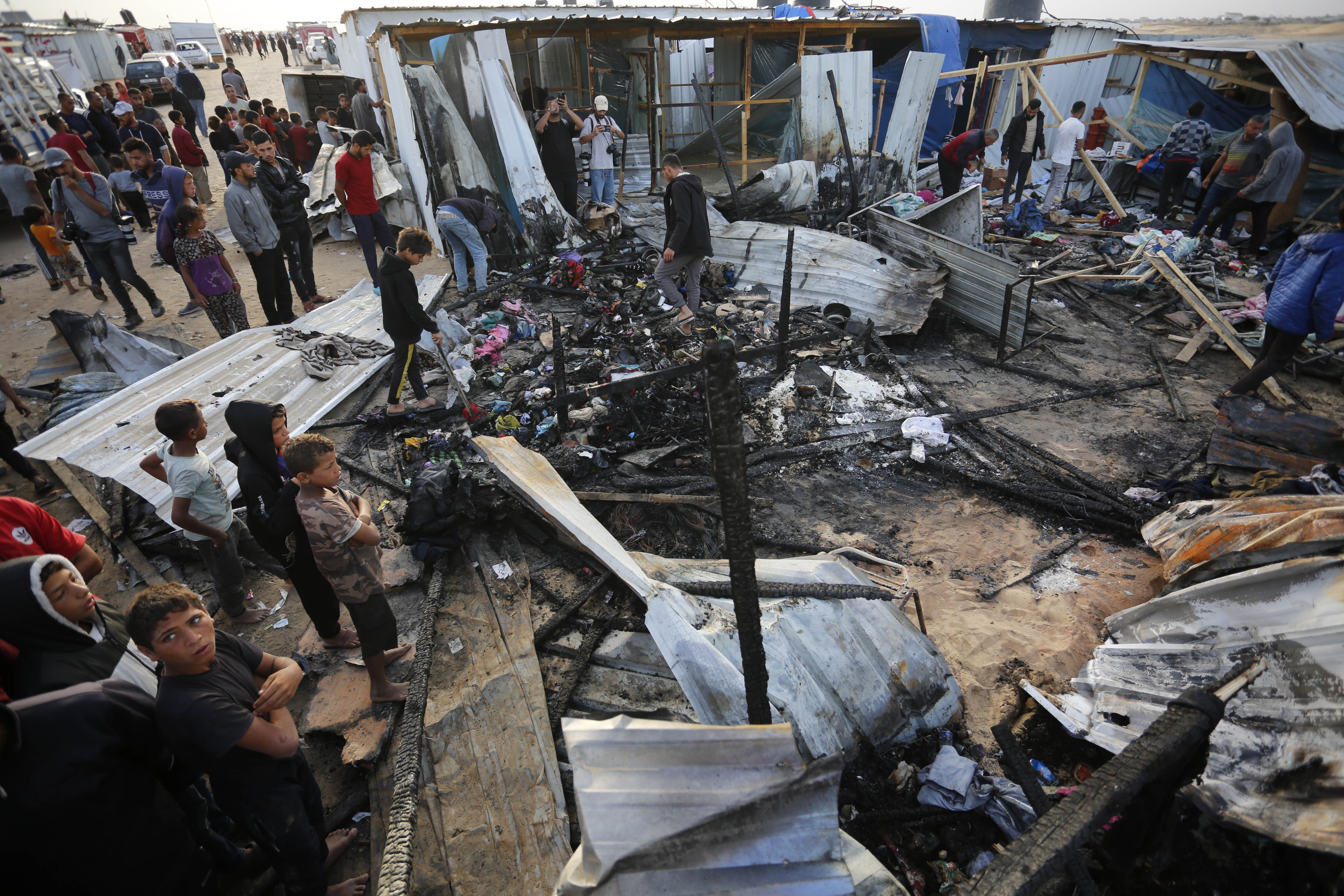 people walk through destroyed building after a fire