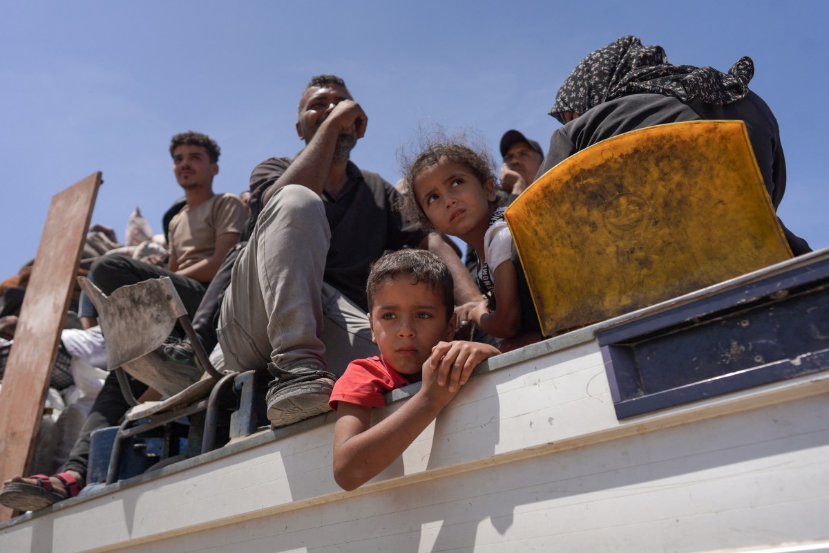 Palestinian who fled Rafah in the southern Gaza Strip ride with their belongings in the back of a truck
