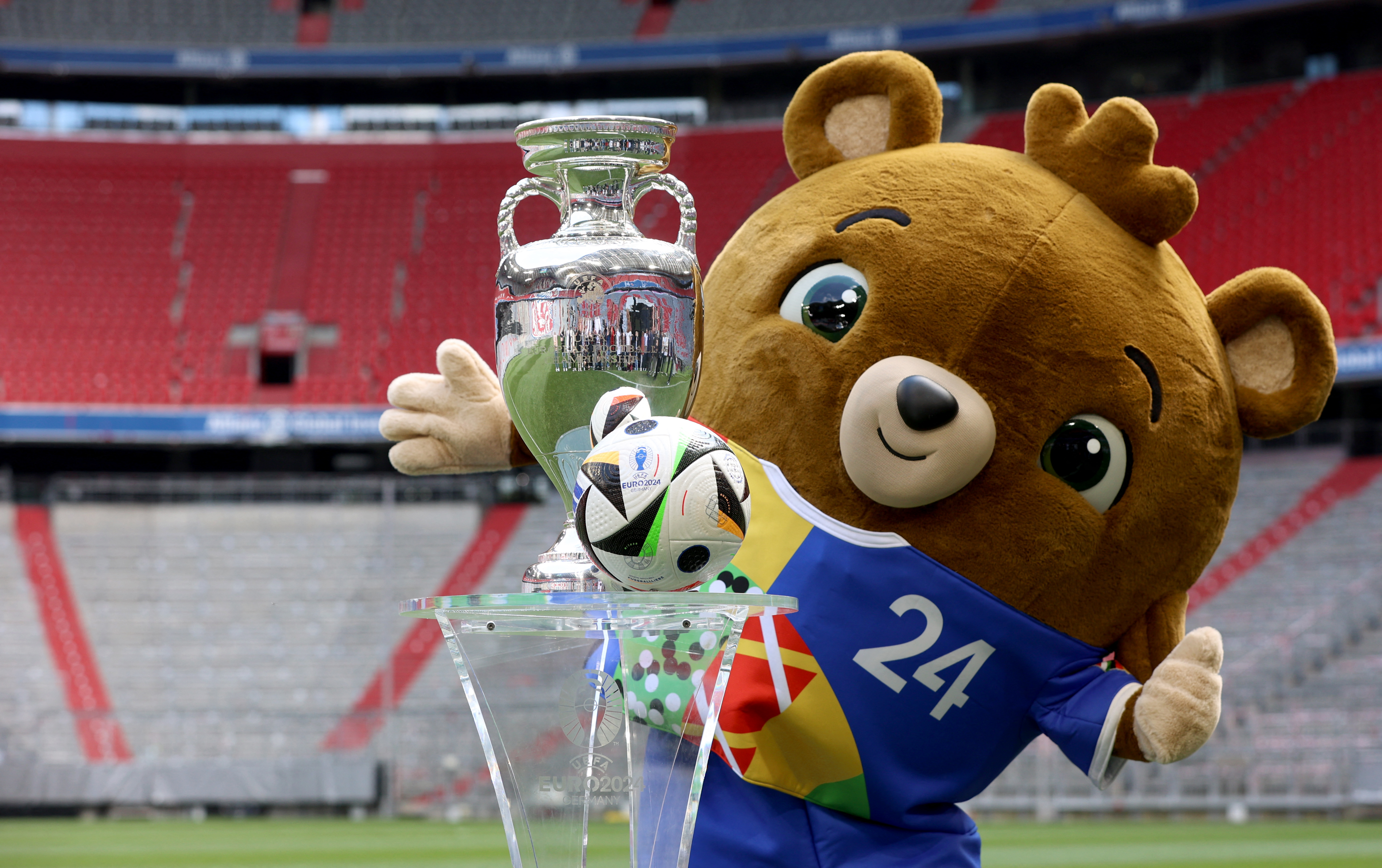 Mascot poses with ball at football stadium.