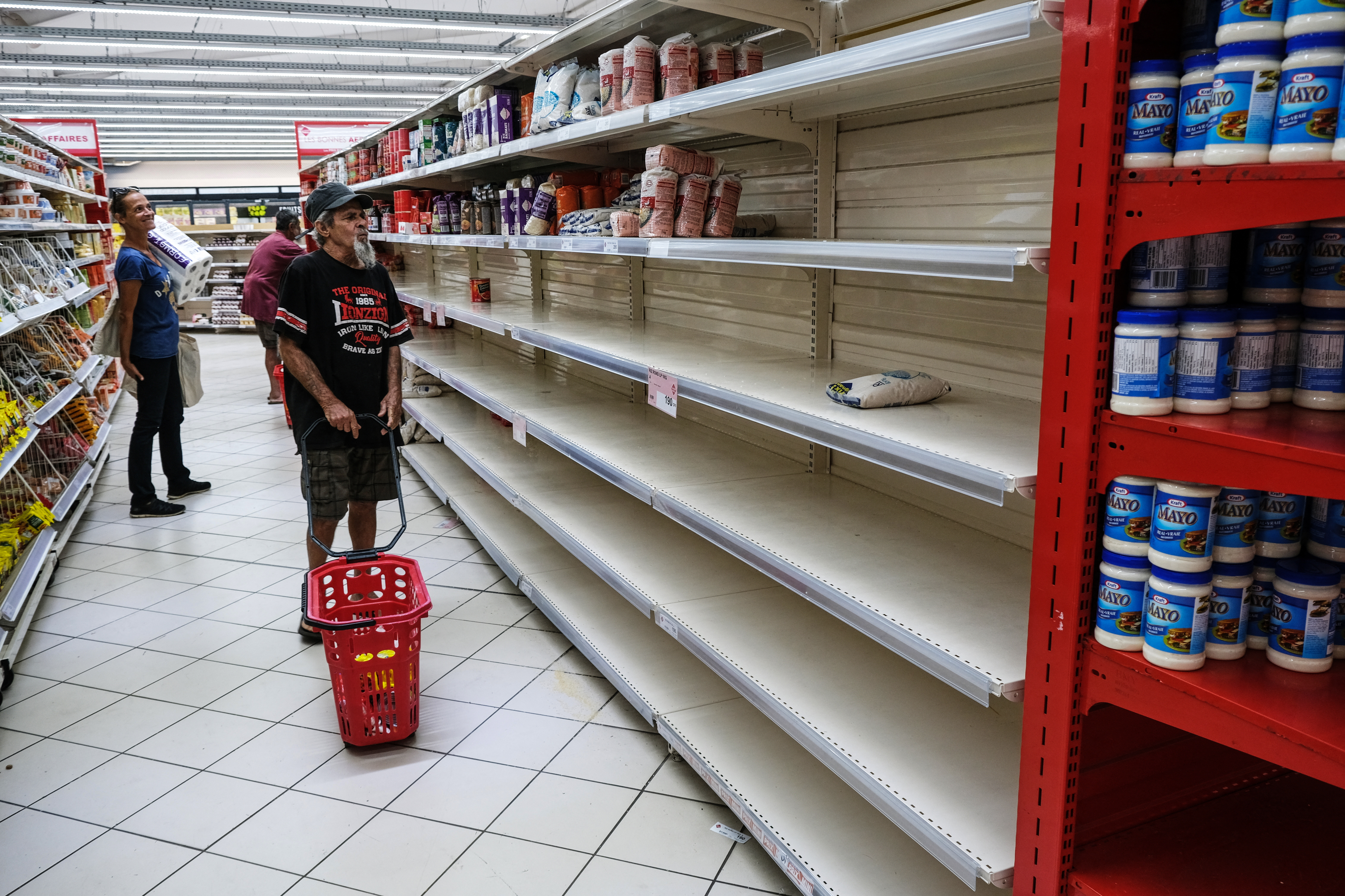People look for groceries and food among nearly empty shelves in a supermarket in the Magenta district of Noumea, France's Pacific territory of New Caledonia, on May 18