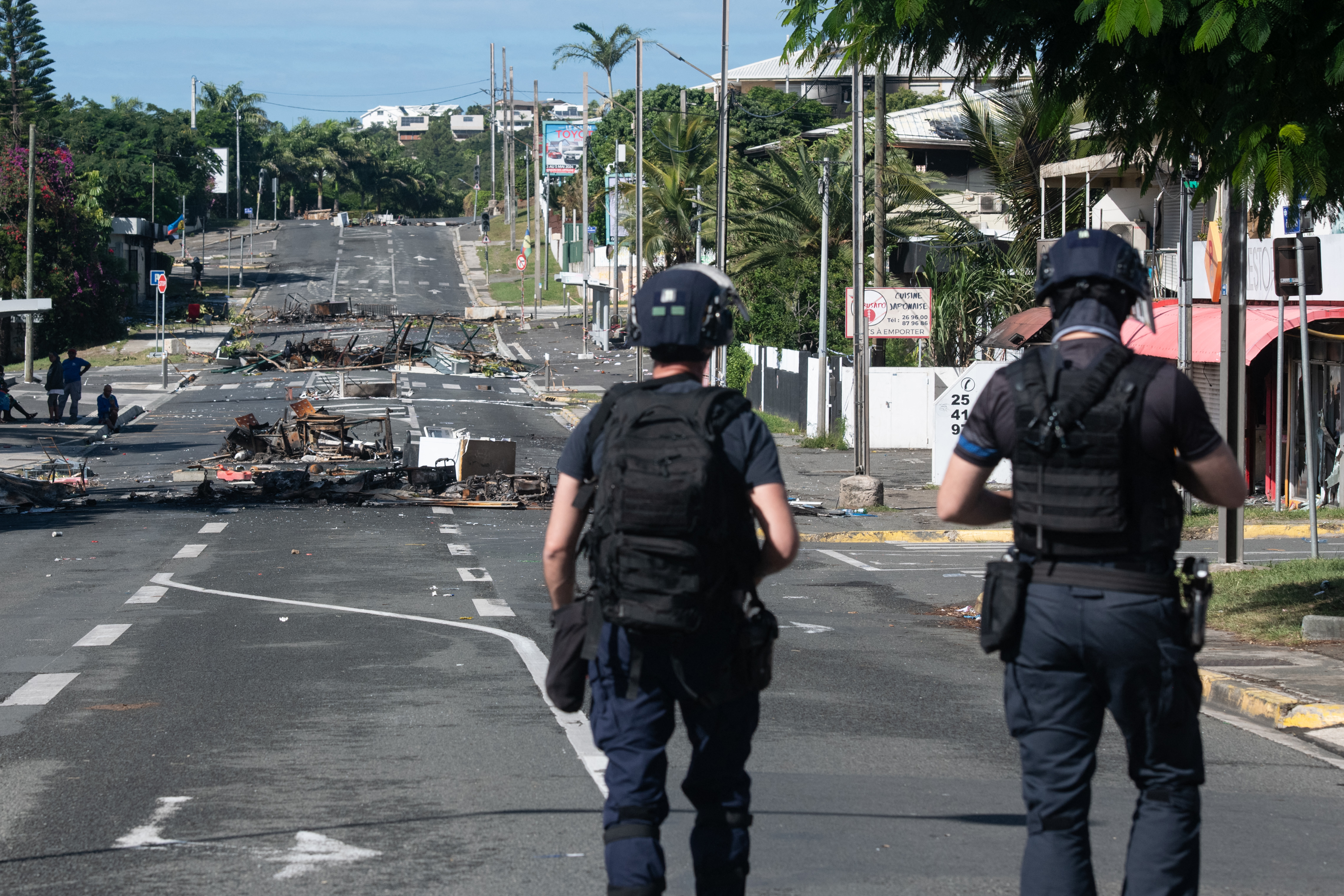 Police patrol a street blocked by debris and burnt out items following overnight unrest in the Magenta district of Noumea, France's Pacific territory of New Caledonia, on May 18, 2024. Hundreds of French security personnel tried to restore order in the Pacific island territory of New Caledonia on May 18, after a fifth night of riots, looting and unrest. (Photo by Delphine Mayeur / AFP)