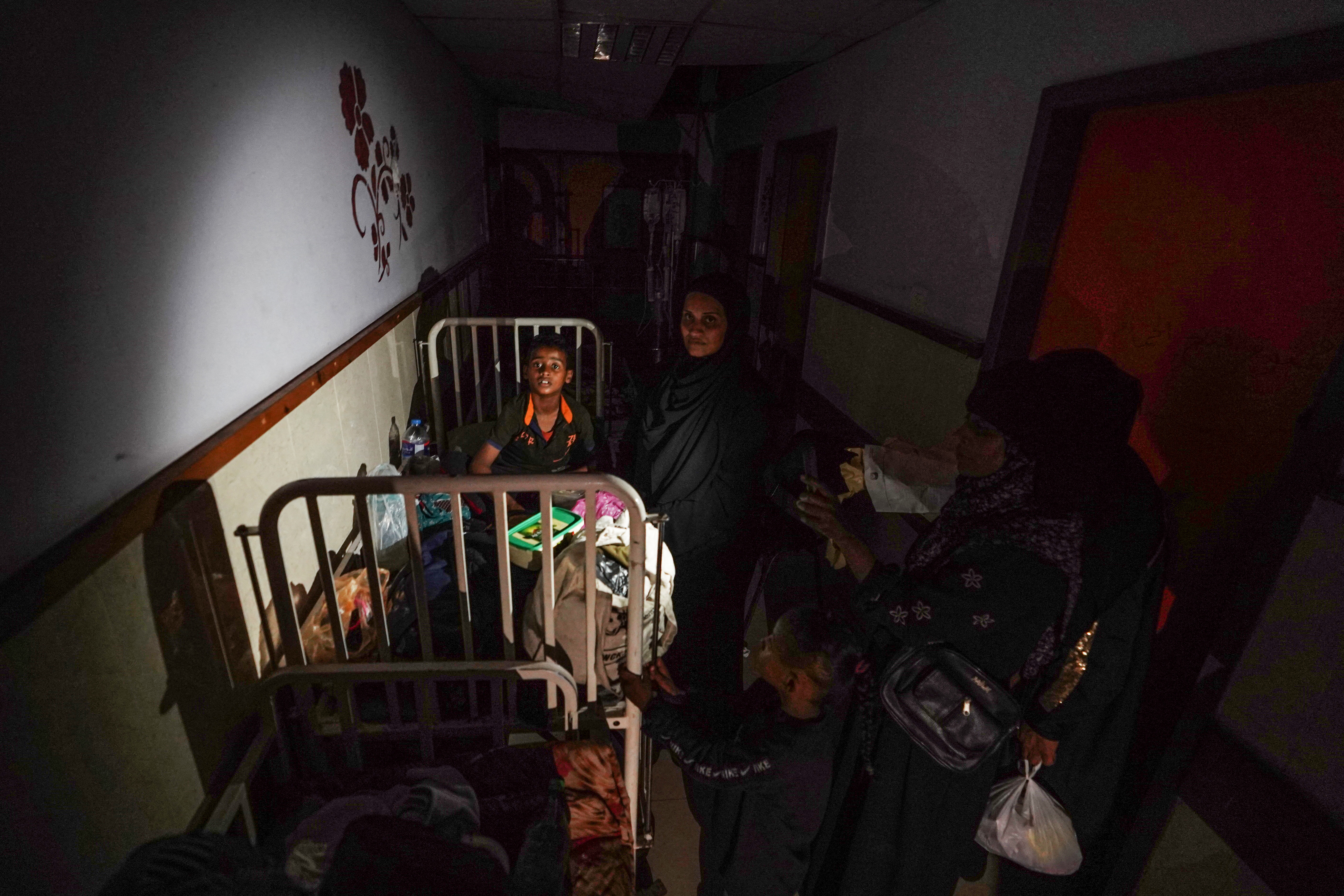 EDITORS NOTE: Graphic content / A patien surrounded by family members sits on a bed in a corridor lit by sunlight seeping through a window, after a partial power cut at the Al-Aqsa Martyrs Hospital in Deir al-Balah on May 23, 2024, amid continuing battles between Israel and Hamas in the Gaza Strip. (Photo by Bashar TALEB / AFP)