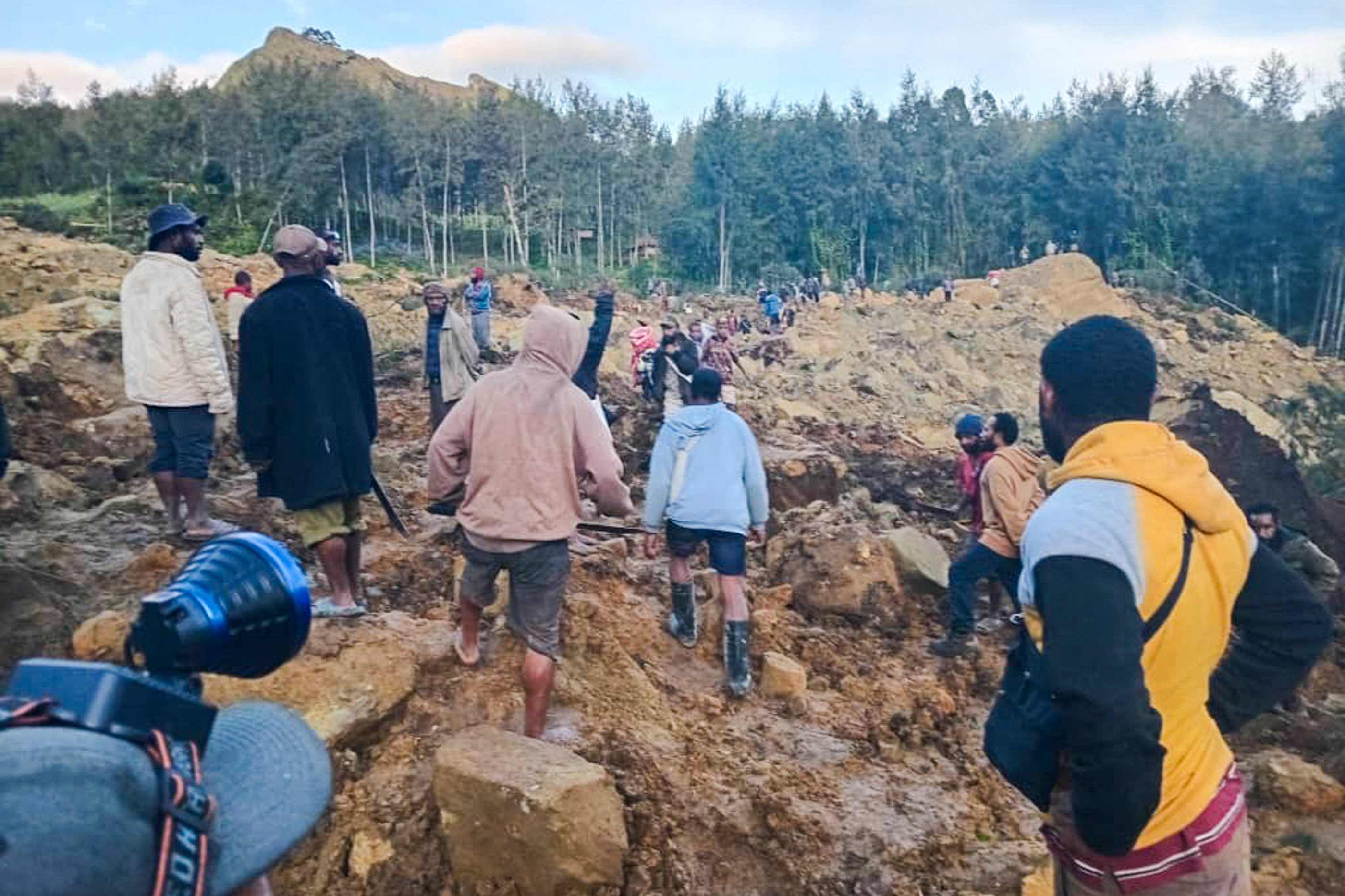 People gather at the site of a landslide in Maip Mulitaka in Papua New Guinea's Enga Province on May 24, 2024. Local officials and aid groups said a massive landslide struck a village in Papua New Guinea's highlands on May 24, with many feared dead. (Photo by AFP)