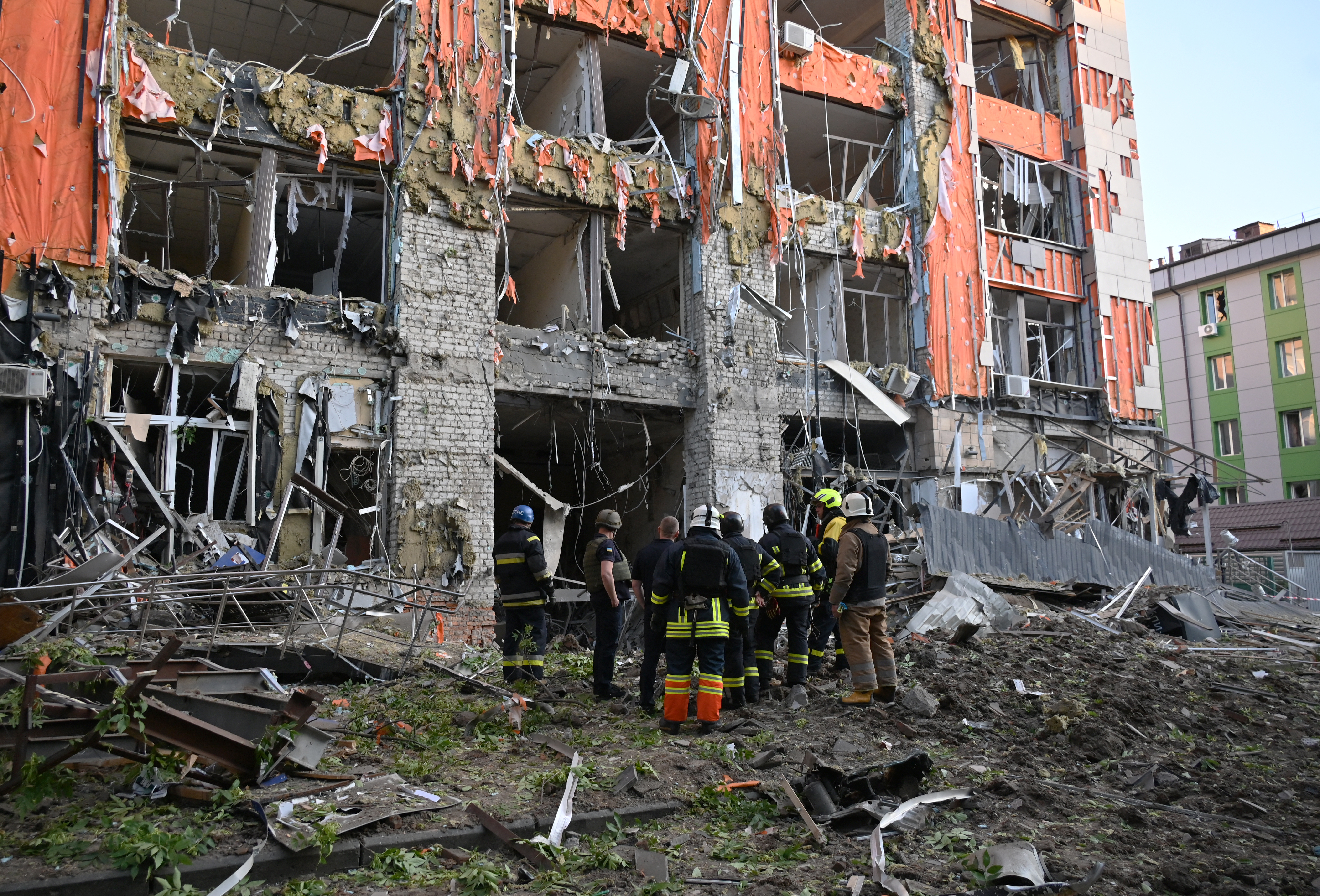 Firefighters inspect a heavily damaged office building following the latest Russian air attack in Kharkiv