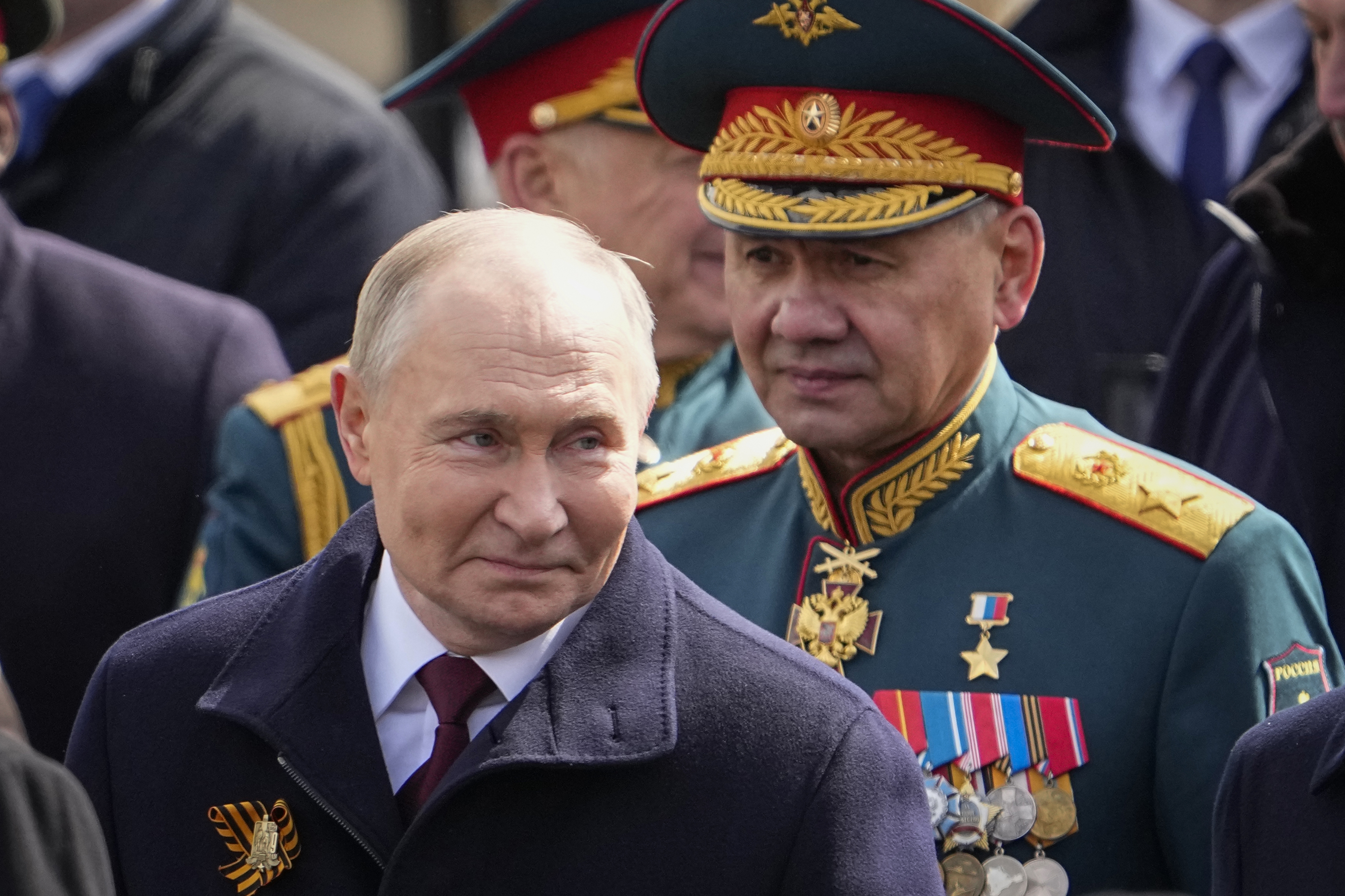 Sergei Shoigu, wearing a military uniform, walks behind Vladimir Putin at the Victory Day parade.