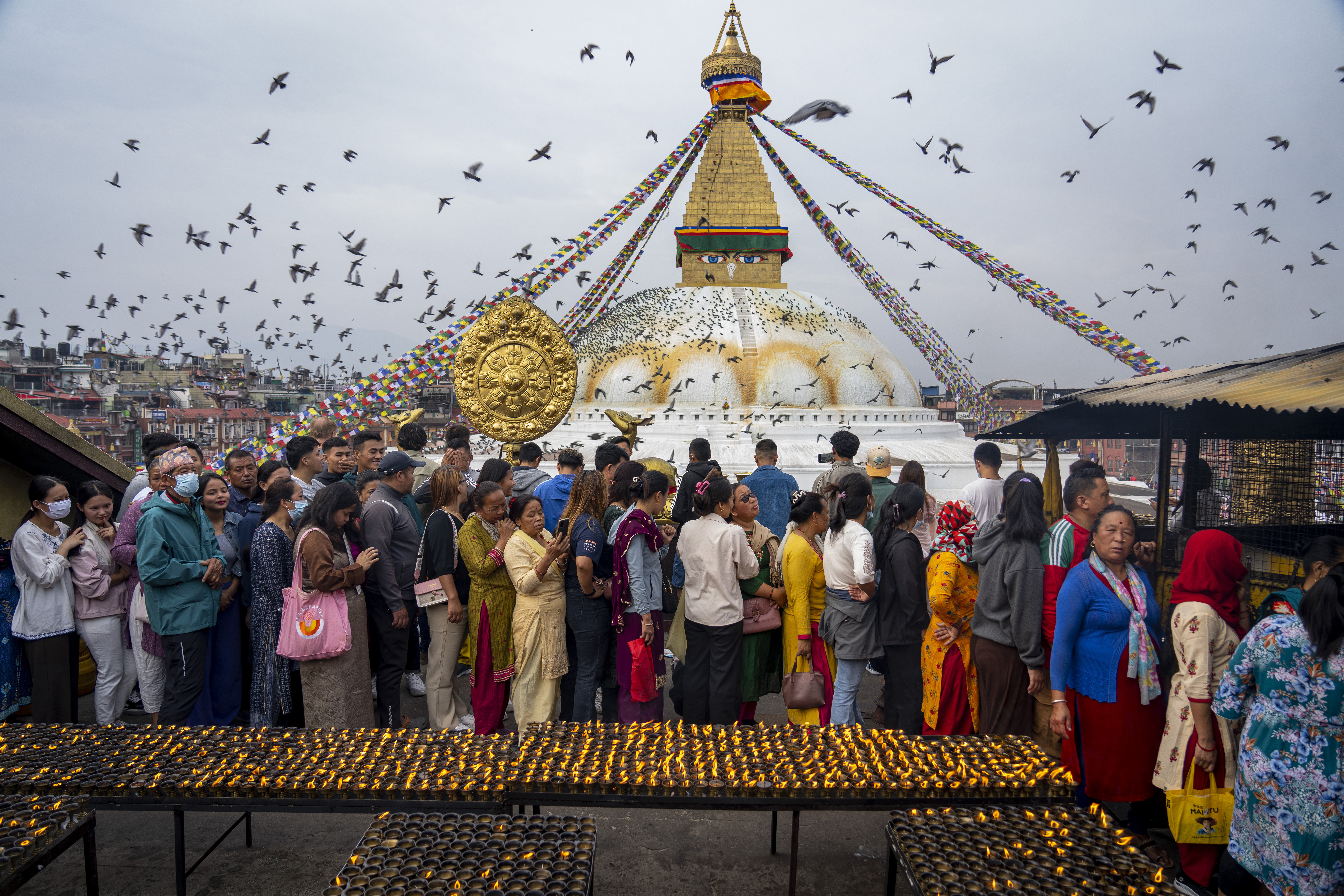 Buddhist devotees stand in a queue to light butter lamps during Buddha Jayanti or Buddha Purnima festival at the Boudhanath Stupa in Kathmandu, Nepal, Thursday, May 23