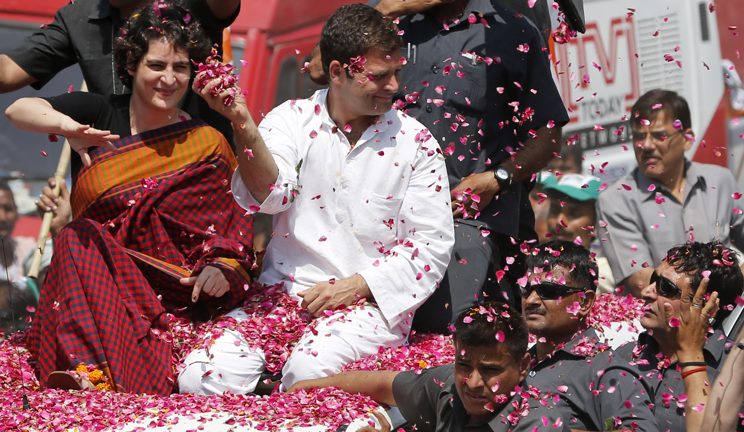 Vice President of Indias ruling Congress party Rahul Gandhi, second right, holds a handful of flower petals to throw back at supporters, with his sister Priyanka Vadra seated by his side as he arrives to file his nomination for the ongoing general elections in Amethi, in the northern Indian state of Uttar Pradesh, Saturday, April 12, 2014. Gandhi, heir to the country's Nehru-Gandhi political dynasty, is leading the struggling party's campaign in the general election. The multiphase voting across the country runs until May 12, with results for the 543-seat lower house of parliament announced May 16. (AP Photo/ Rajesh Kumar Singh)