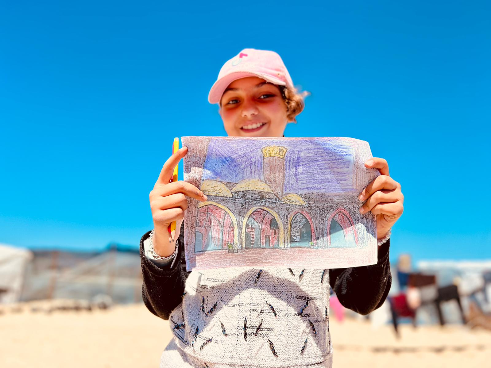 Ibtisama (not her real name), 13, stands holding her vibrant picture of a red and yellow Great Omari Mosque under a brilliant blue sky. The oldest mosque in the Gaza Strip, based in Daraj, Gaza City, is also known as the 'Great Mosque of Gaza' but now lies in ruins.