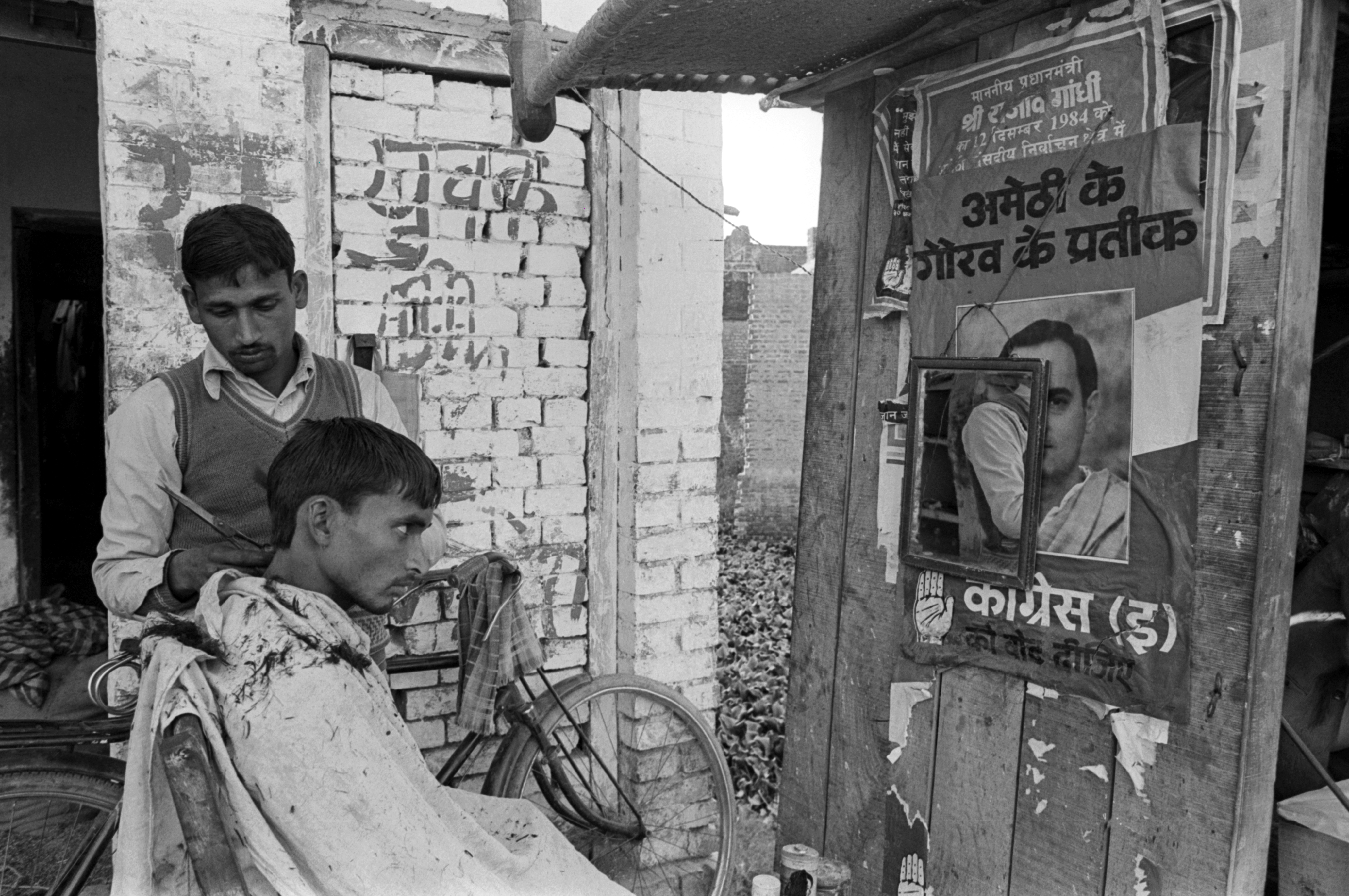 An election campaign poster of Rajiv Gandhi serves as decoration in this makeshift Indian barbershop.
