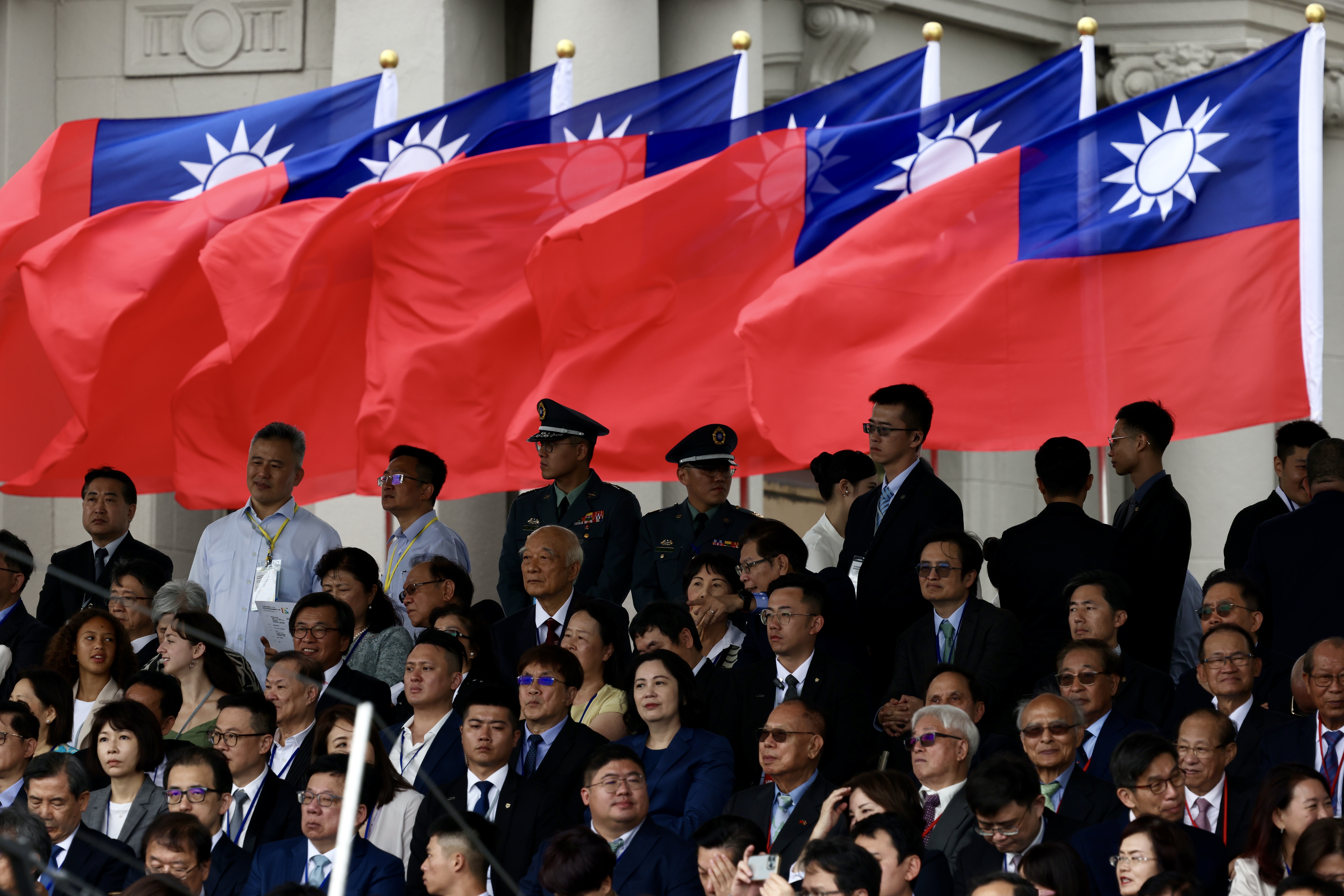 Foreign dignitaries sitting beneath Taiwan flags.