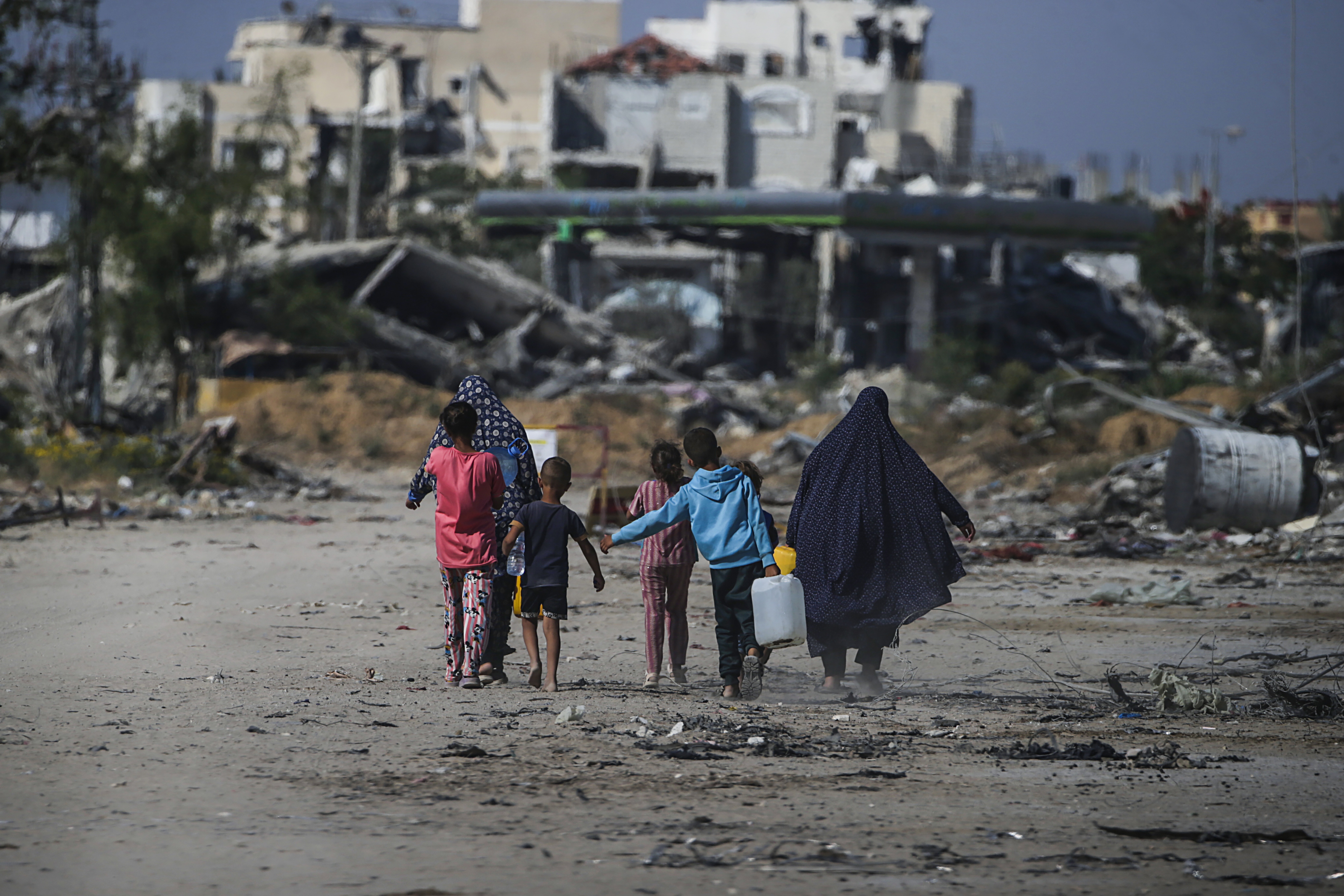 epa11392513 Internally displaced Palestinians walk next to destroyed buildings in Khan Younis, southern Gaza Strip, 05 June 2024. More than 36,000 Palestinians and over 1,400 Israelis have been killed, according to the Palestinian Health Ministry and the Israel Defense Forces (IDF), since Hamas militants launched an attack against Israel from the Gaza Strip on 07 October 2023, and the Israeli operations in Gaza and the West Bank which followed it.