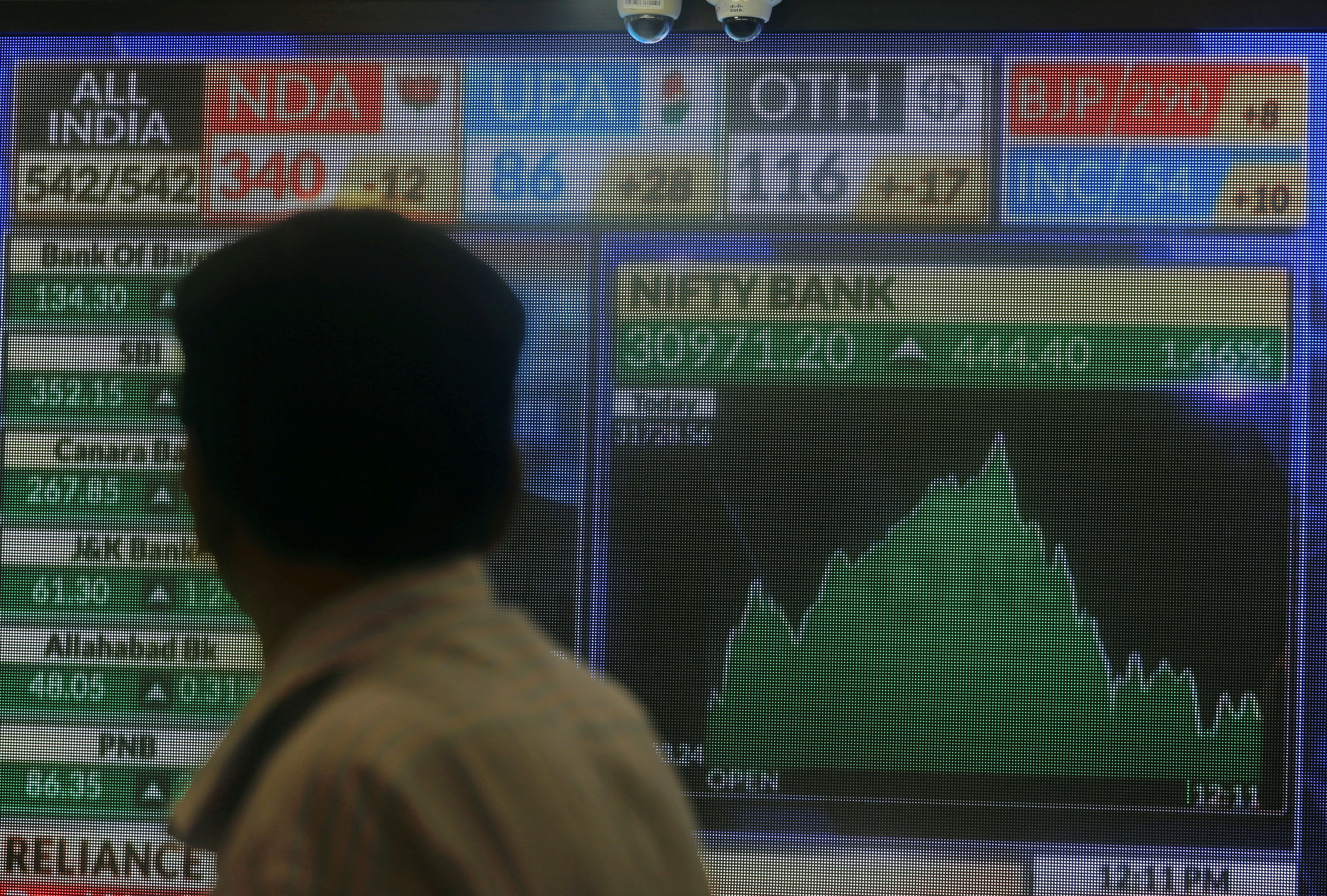 FILE PHOTO: A man looks at a screen displaying news of markets update inside the Bombay Stock Exchange (BSE) building in Mumbai, India, May 23, 2019
