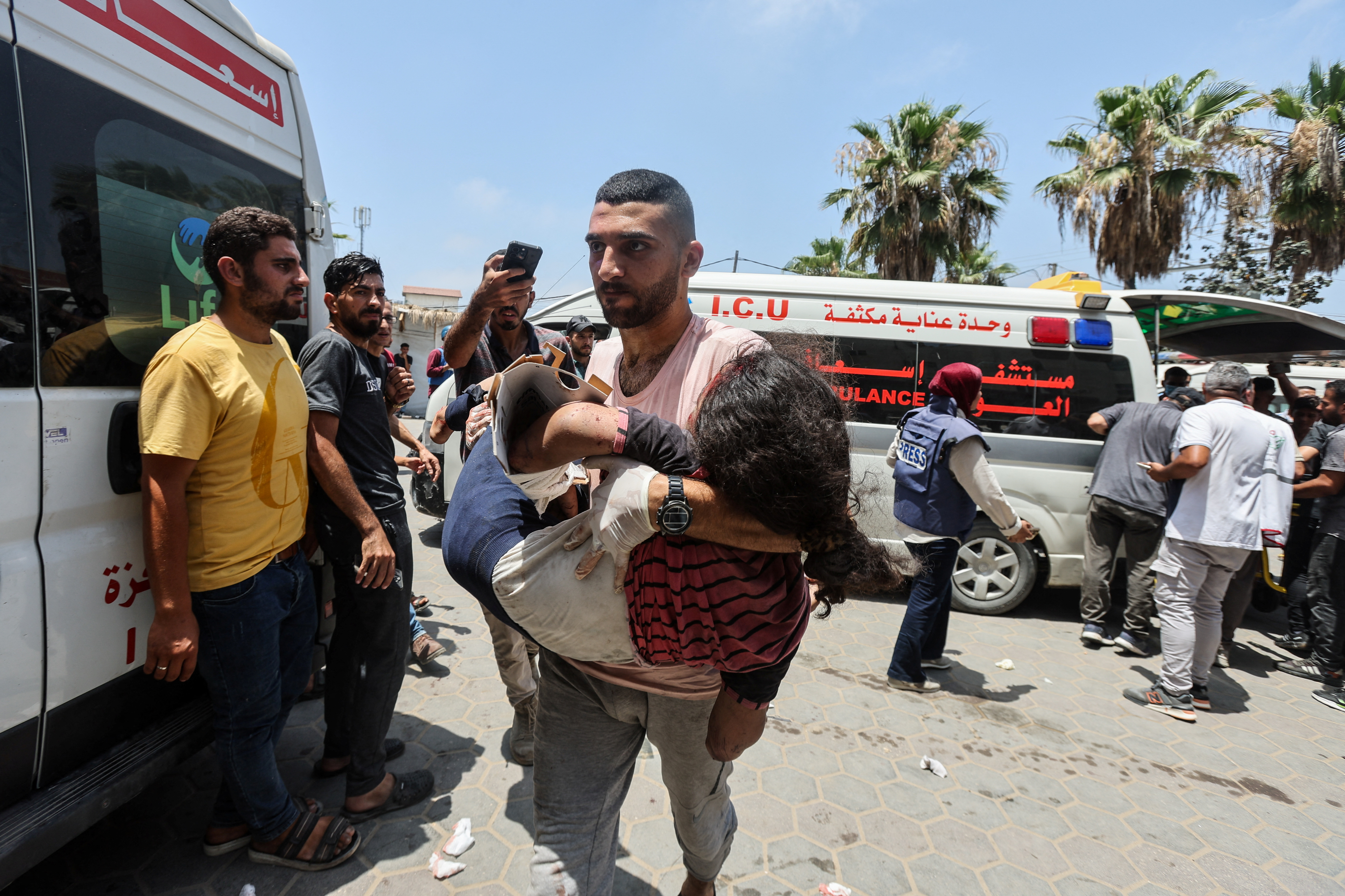Palestinian man carries a casualty in the aftermath of an Israeli strike, amid the Israel-Hamas conflict, at Al-Aqsa Martyrs Hospital in Deir Al-Balah, in the central Gaza Strip, June 8