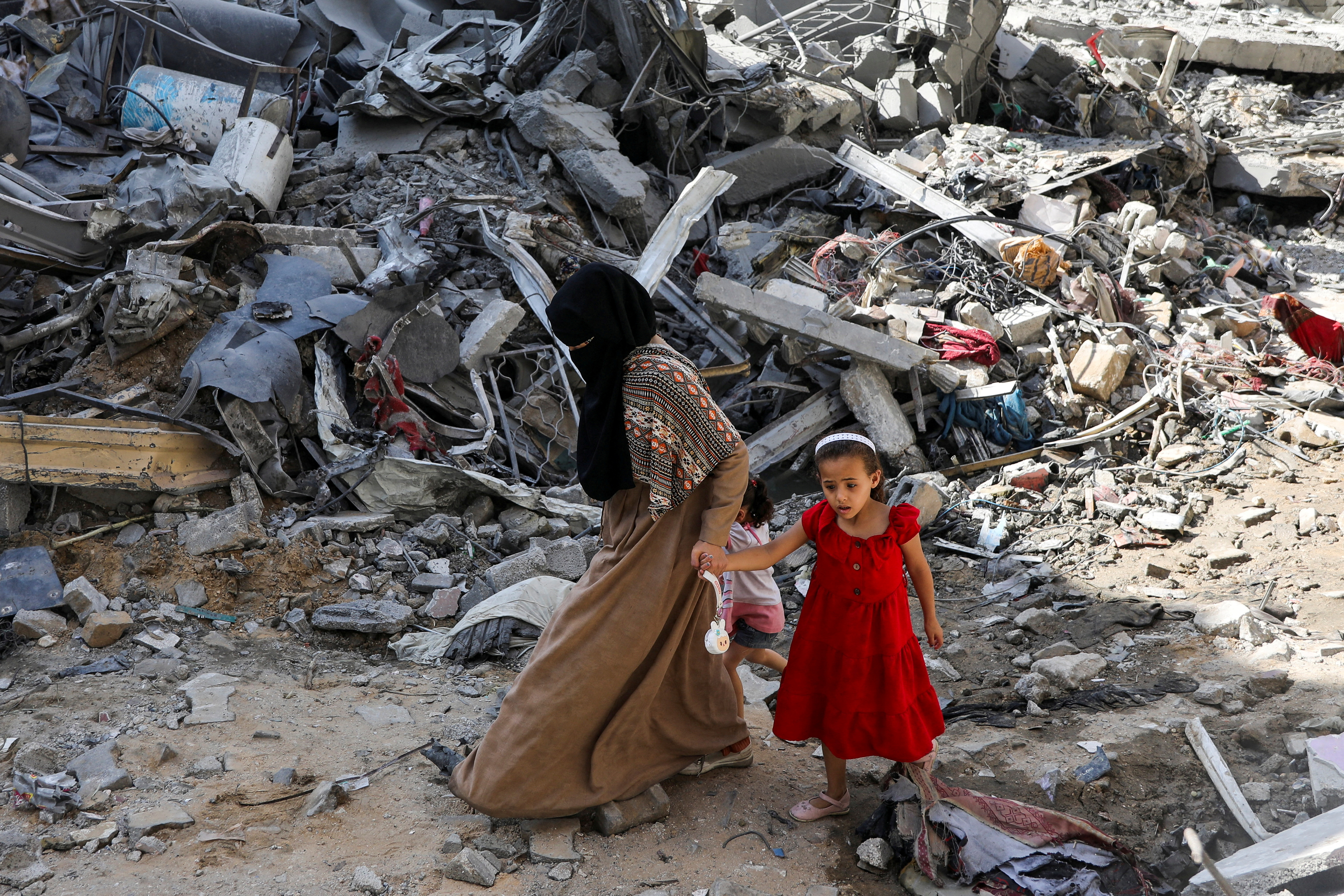 A woman and child walk among debris, aftermath of Israeli strikes