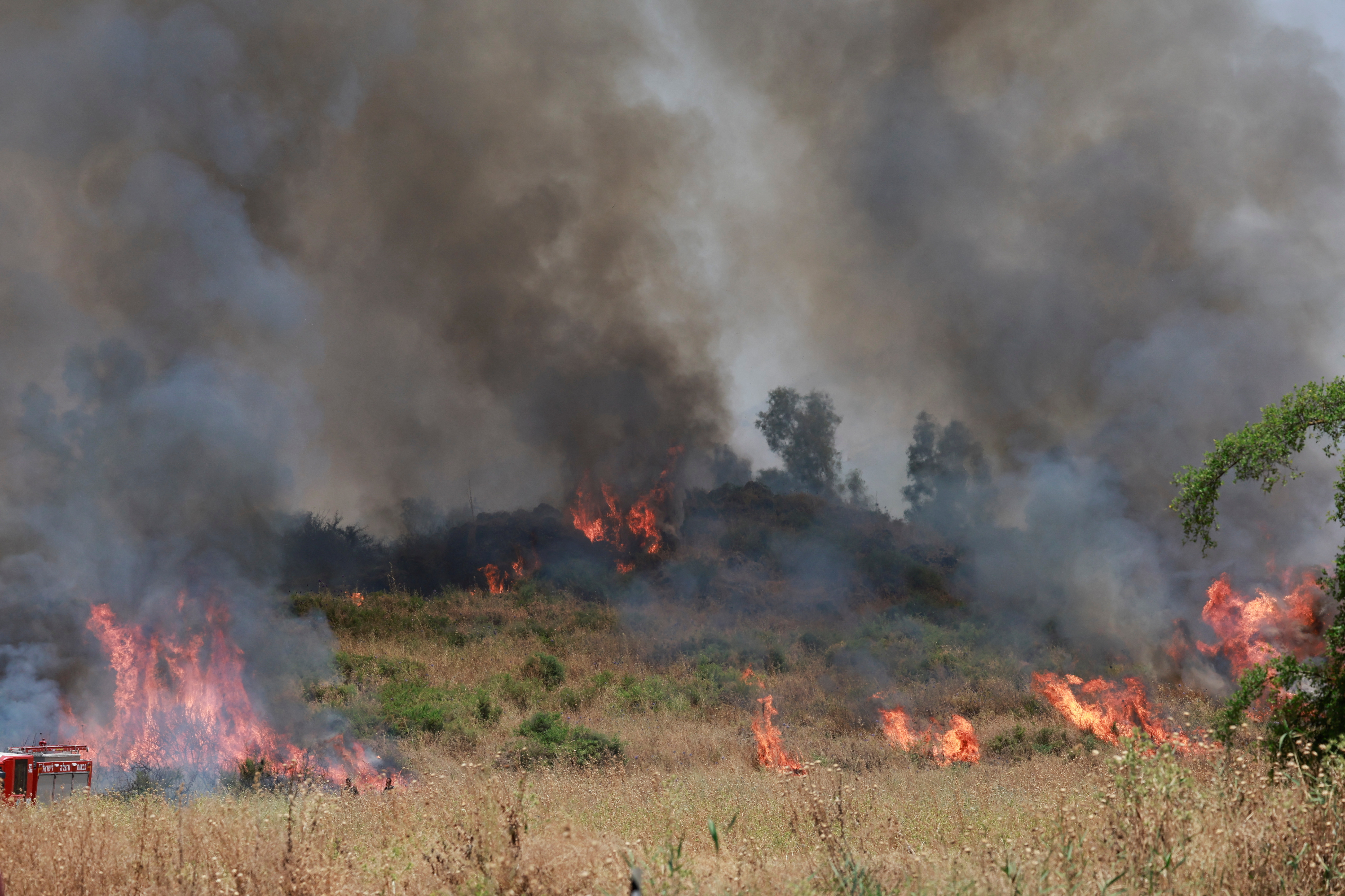 Firefighters respond to a fire near a rocket attack from Lebanon, amid ongoing cross-border hostilities between Hezbollah and Israeli forces, near Kiryat Shmona