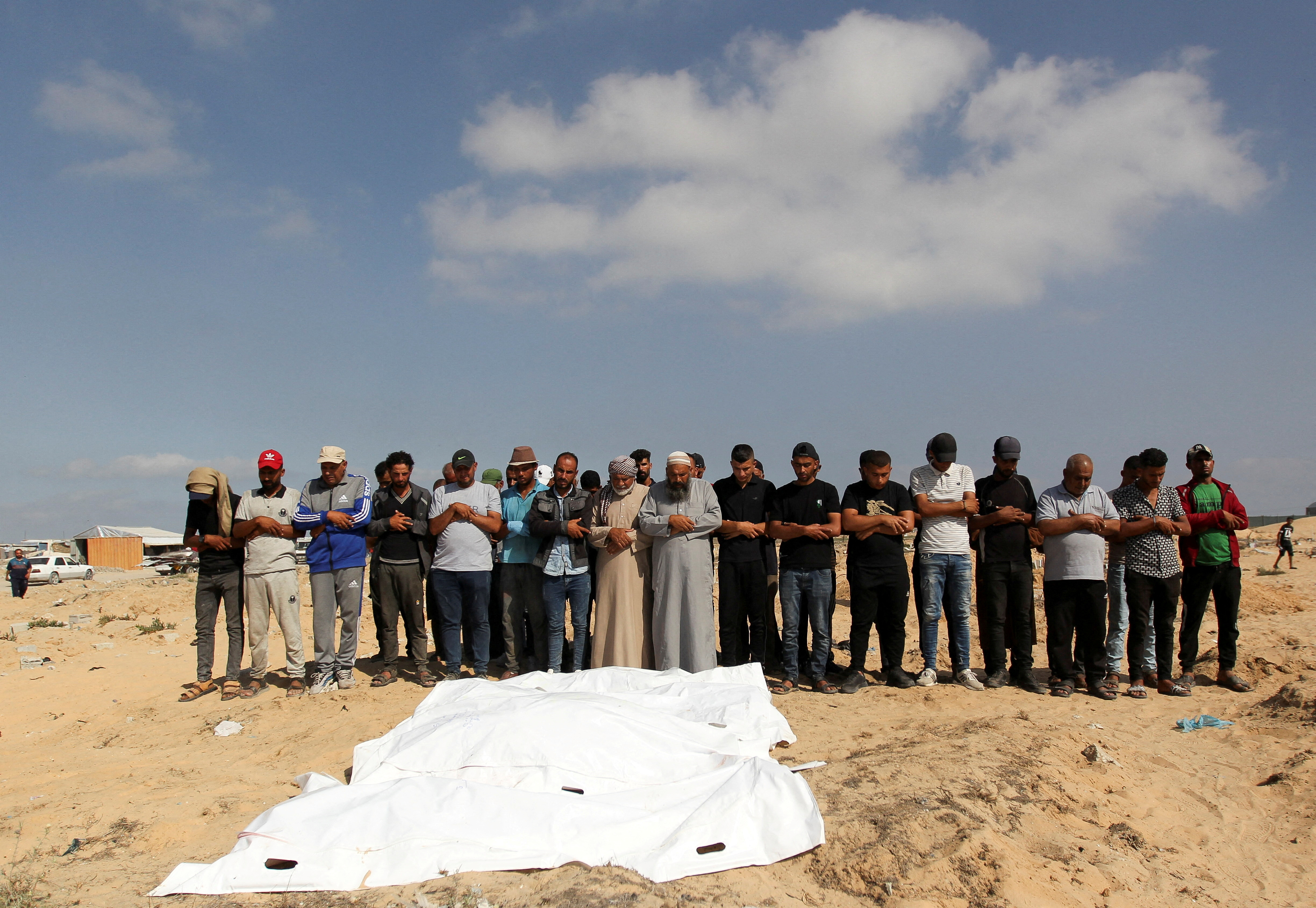 Mourners pray next to the bodies of Palestinians killed in Israeli strikes