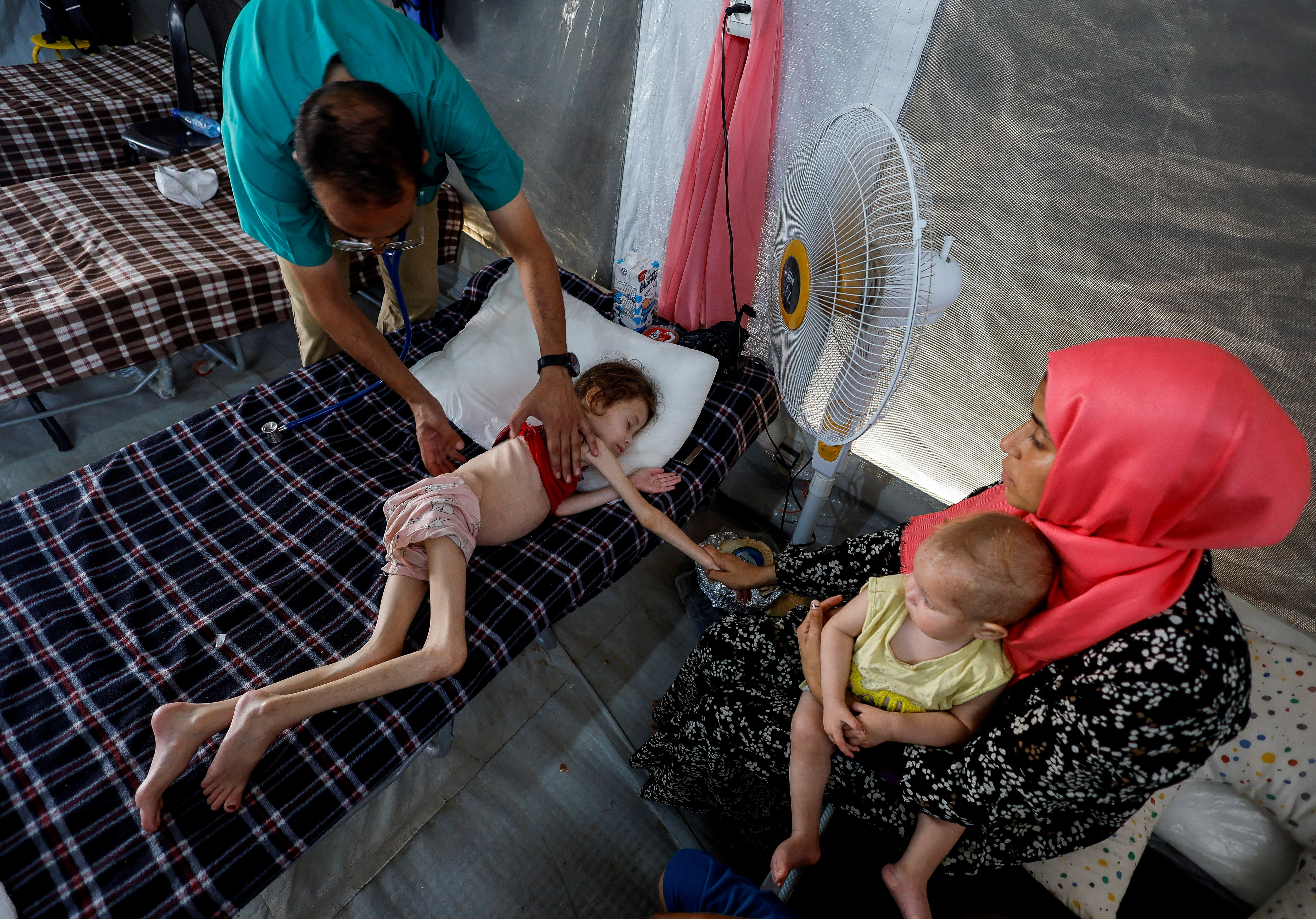 A doctor checks Jana Ayad, a malnourished Palestinian girl, as she receives treatment at the International Medical Corps field hospital