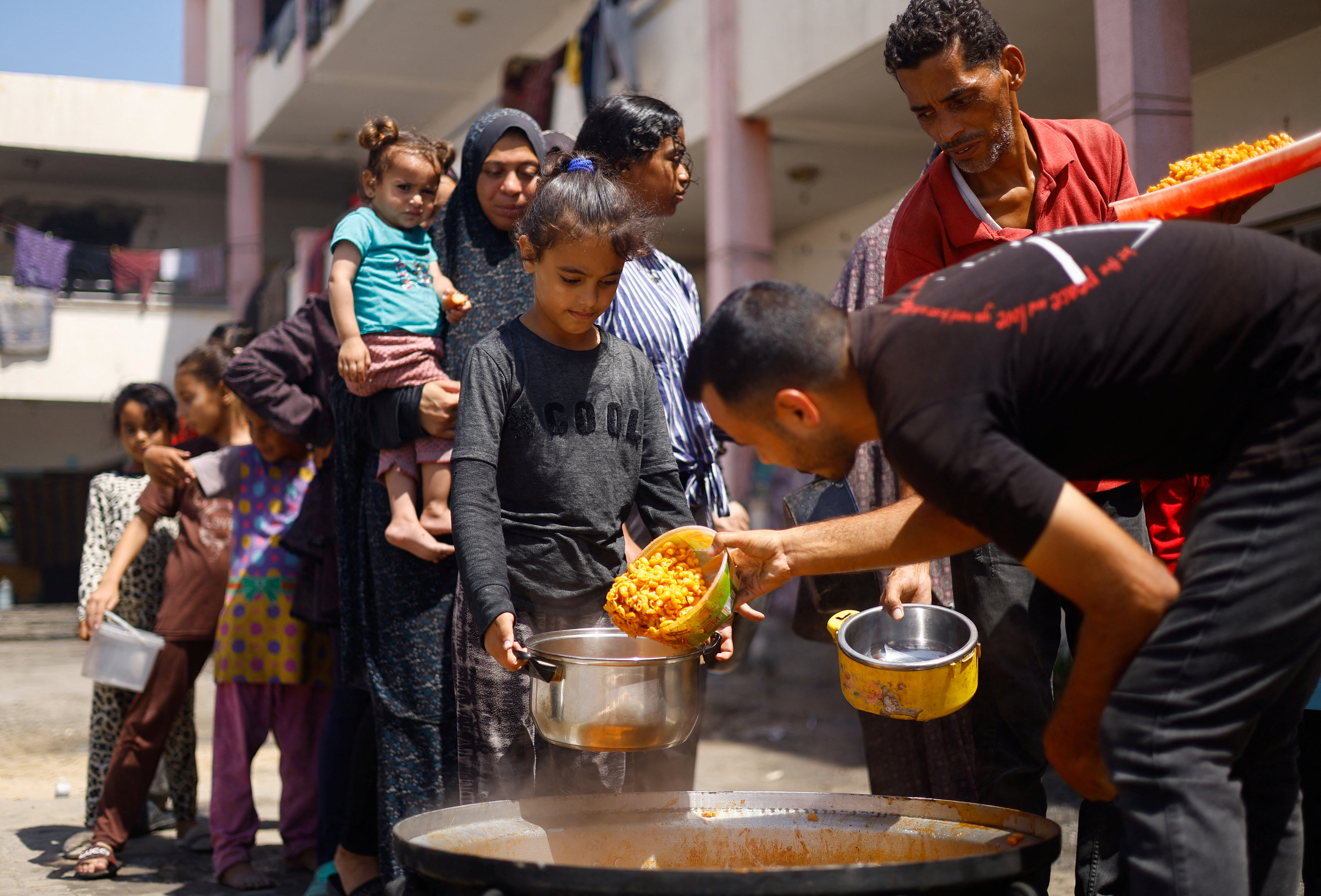 Palestinians gather to receive food cooked by a charity kitchen, amid food scarcity